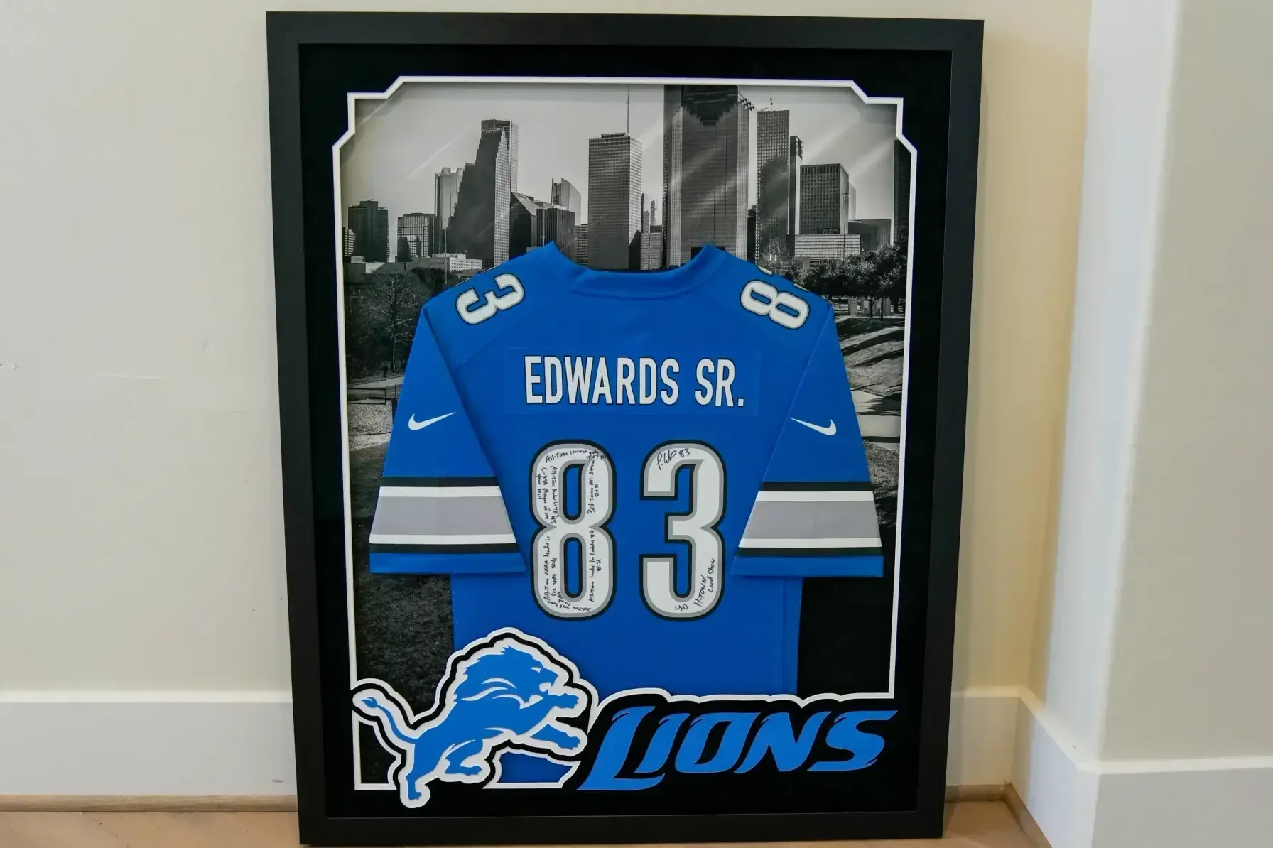 Framed Detroit Lions jersey, blue number 83 with “EDWARDS SR.”, displayed against city skyline background