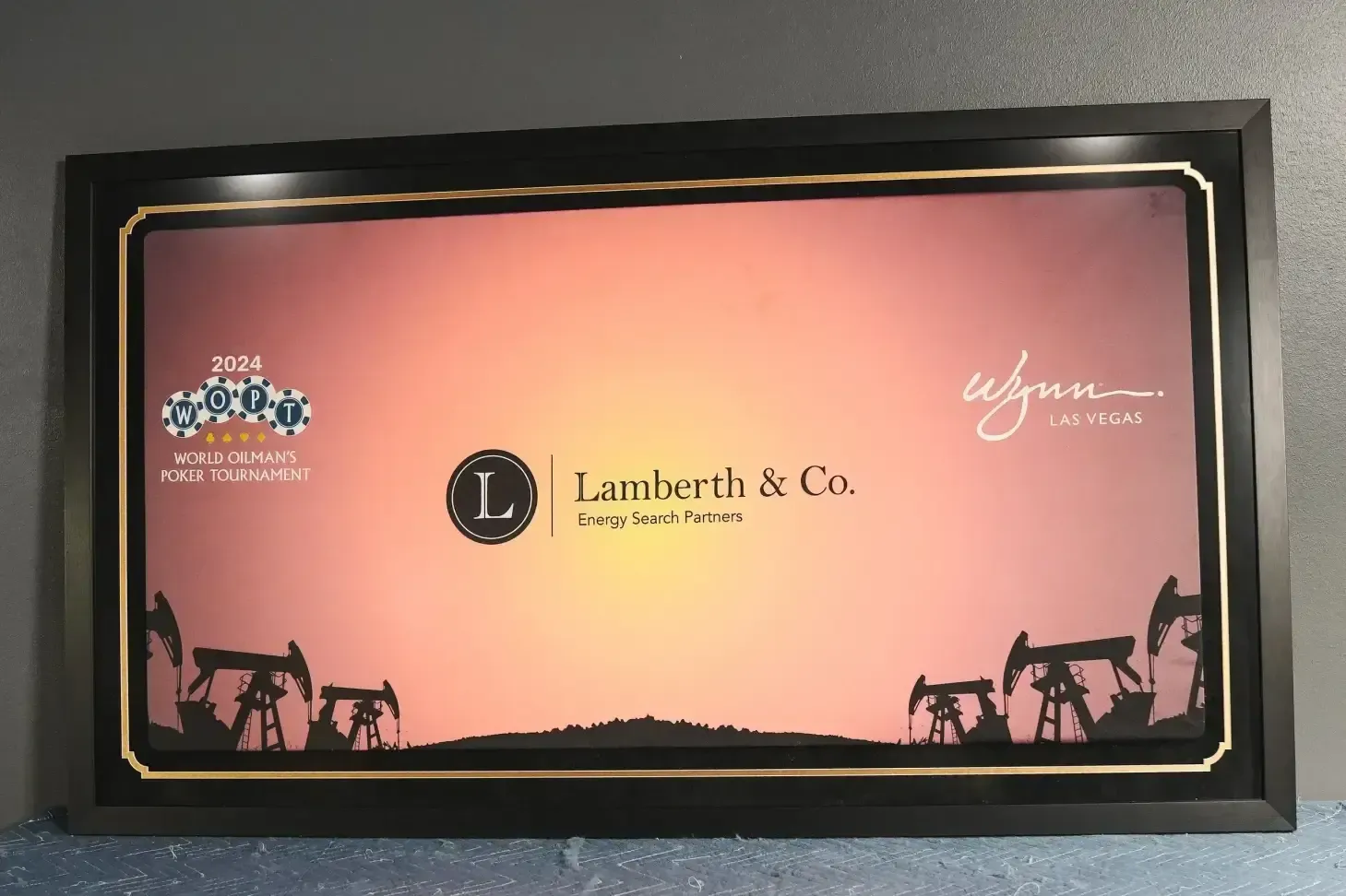 Framed pink-and-black Lambert & Co. artwork with oil rigs silhouetted along the bottom
