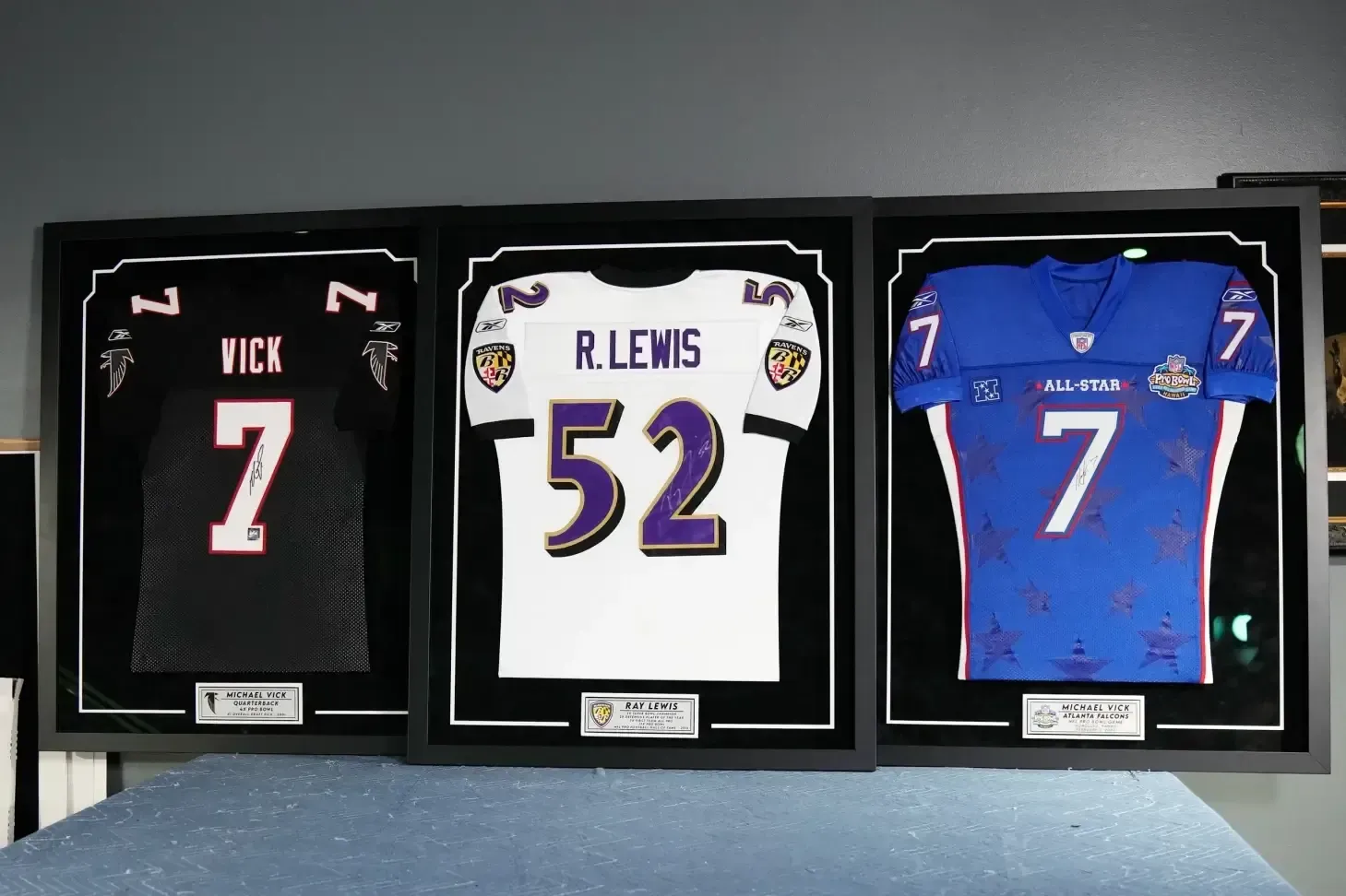 Three framed sports jerseys displayed side by side: black #7, white #52, and blue #7.