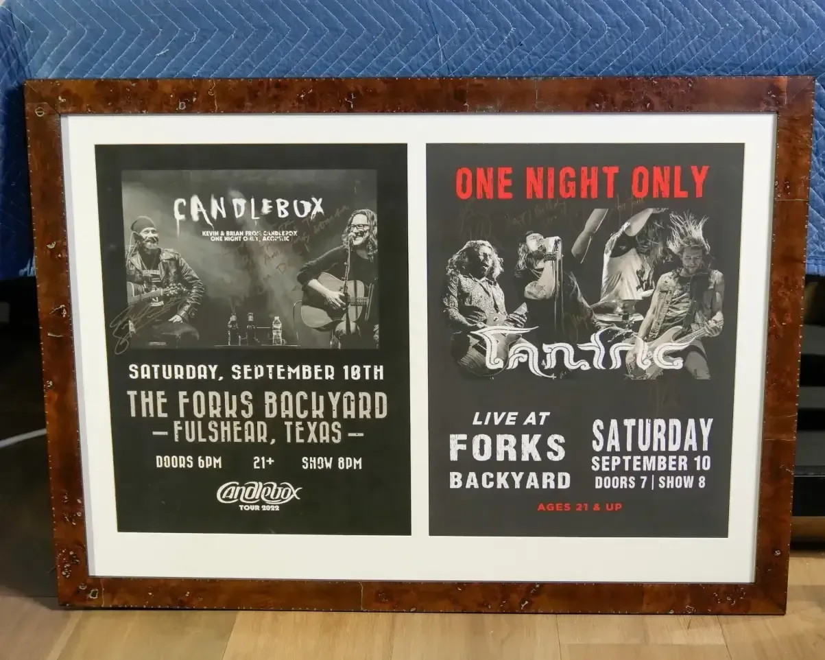 Framed photo of two black-and-white concert posters on a blue fabric background.