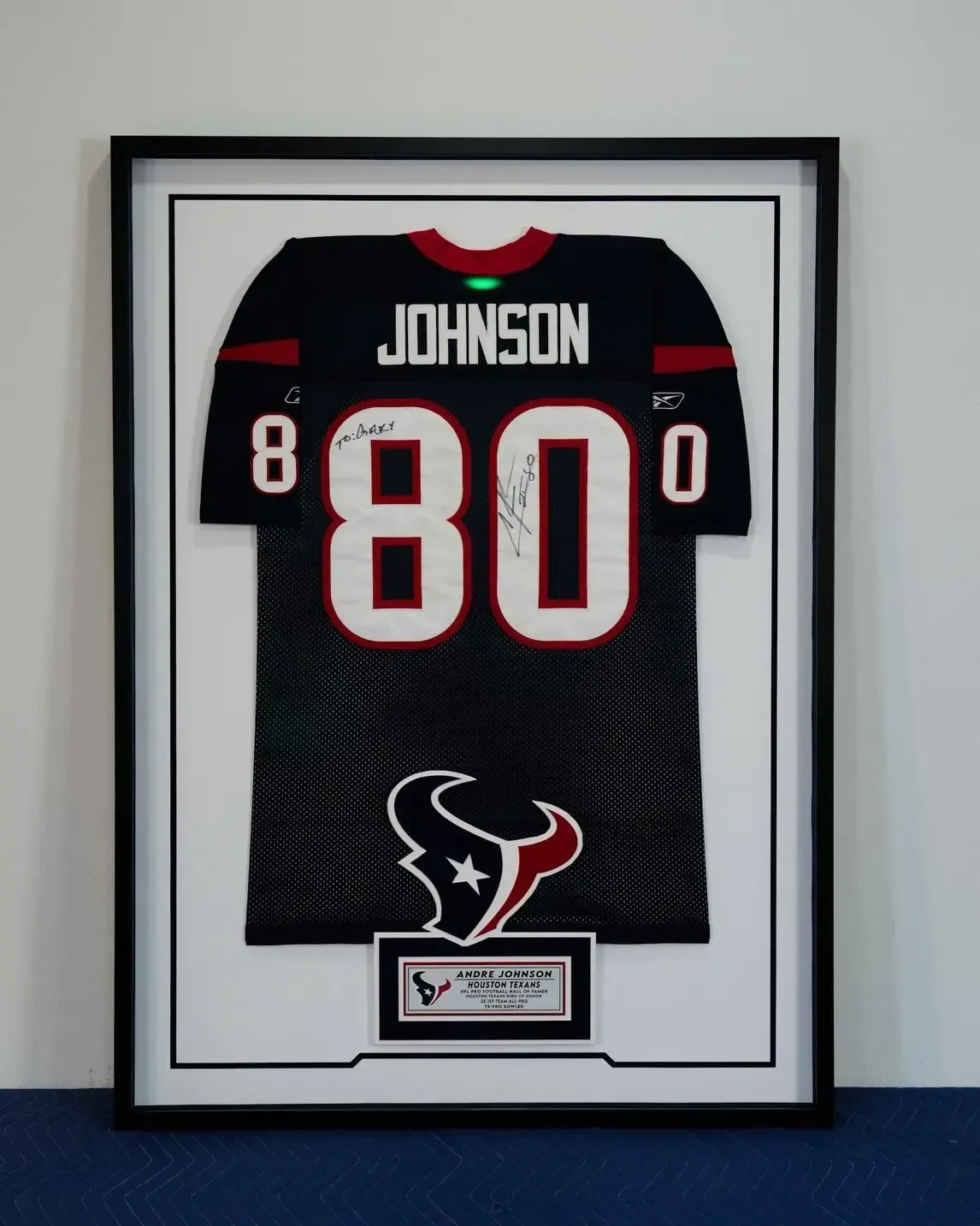 Framed Houston Texans jersey with “Johnson” and number 80 on a white wall.