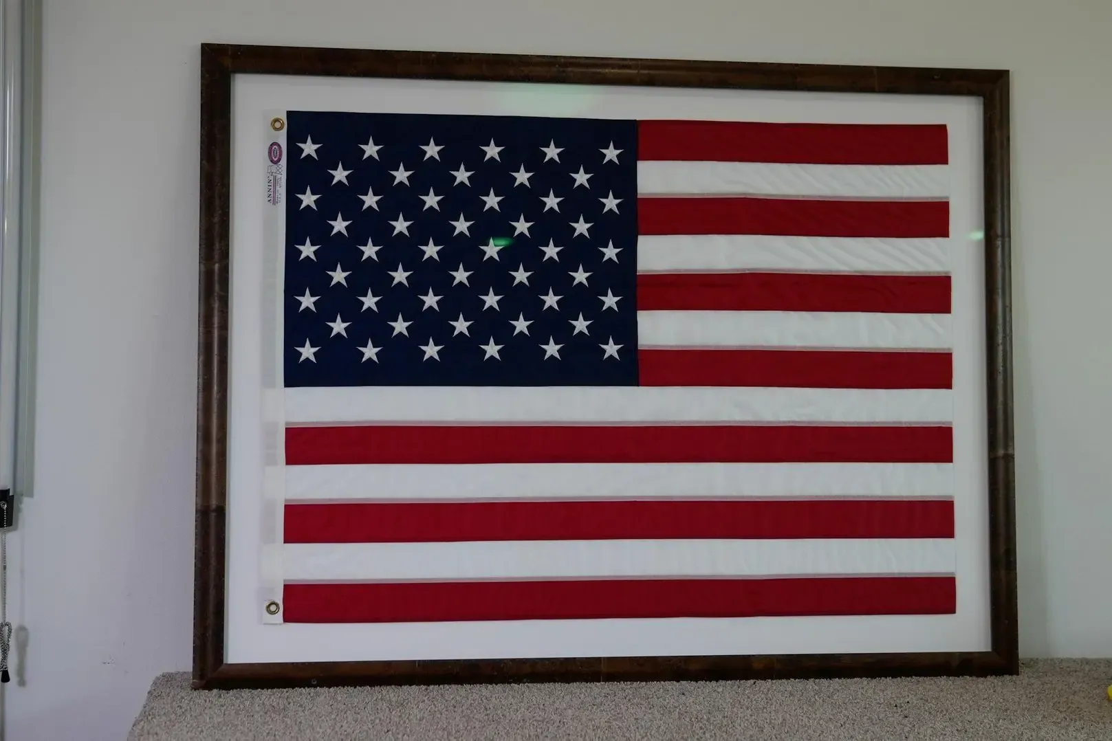 Framed American flag on a wall, with stars and red-and-white stripes.