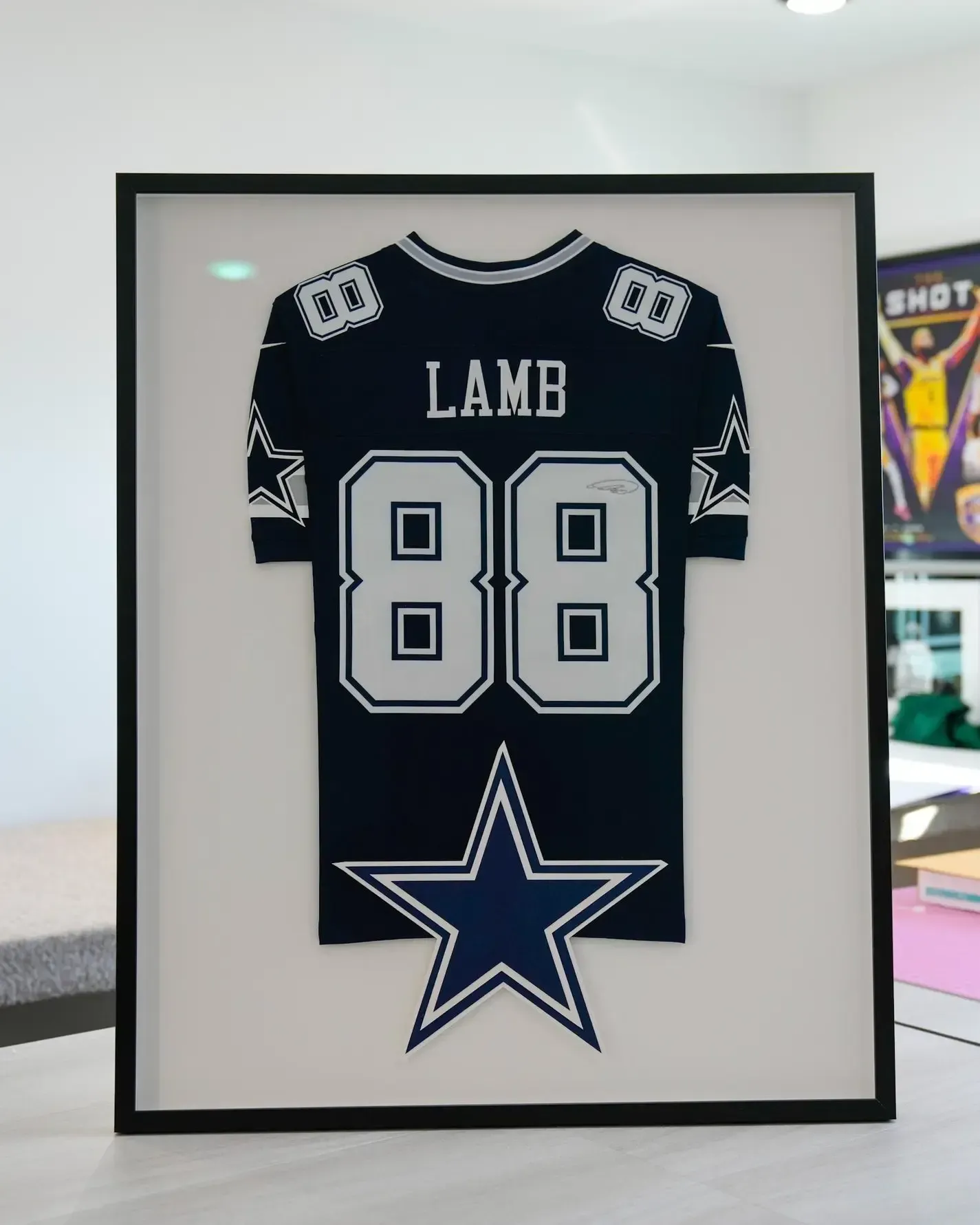 Framed Dallas Cowboys jersey with “LAMB 88” and a large star logo on a white wall