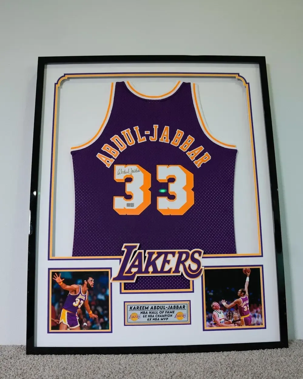 Framed Lakers jersey display with purple No. 33 and Abdul-Jabbar name, with photos below