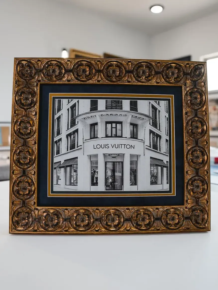 Framed black-and-white storefront photo in an ornate gold frame on a wall