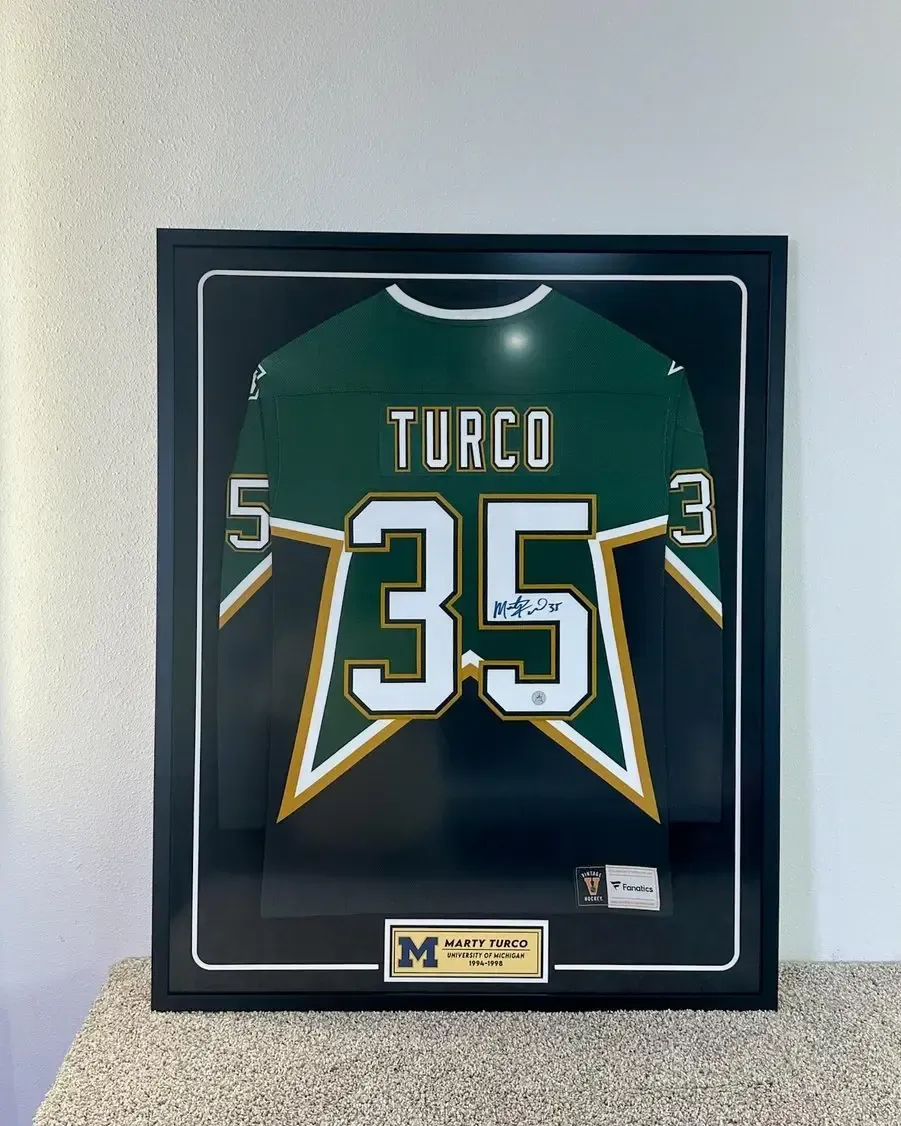 Framed green and black Torco sports jersey with number 35 and white numbers 5 and 3 on a wall