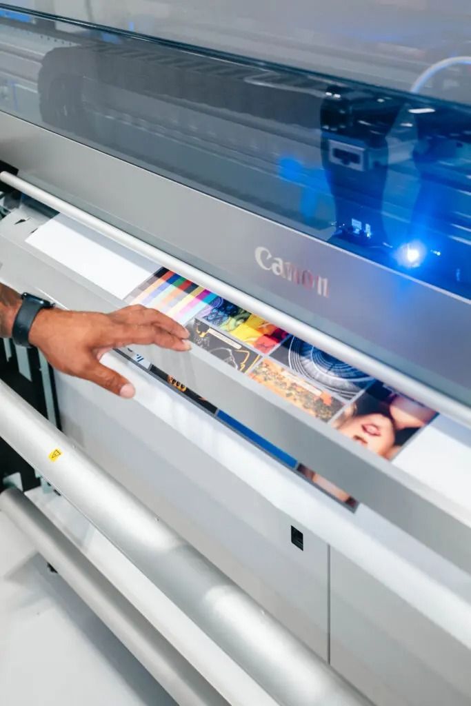 Person loading printed material into a large-format printer with blue-lit cover