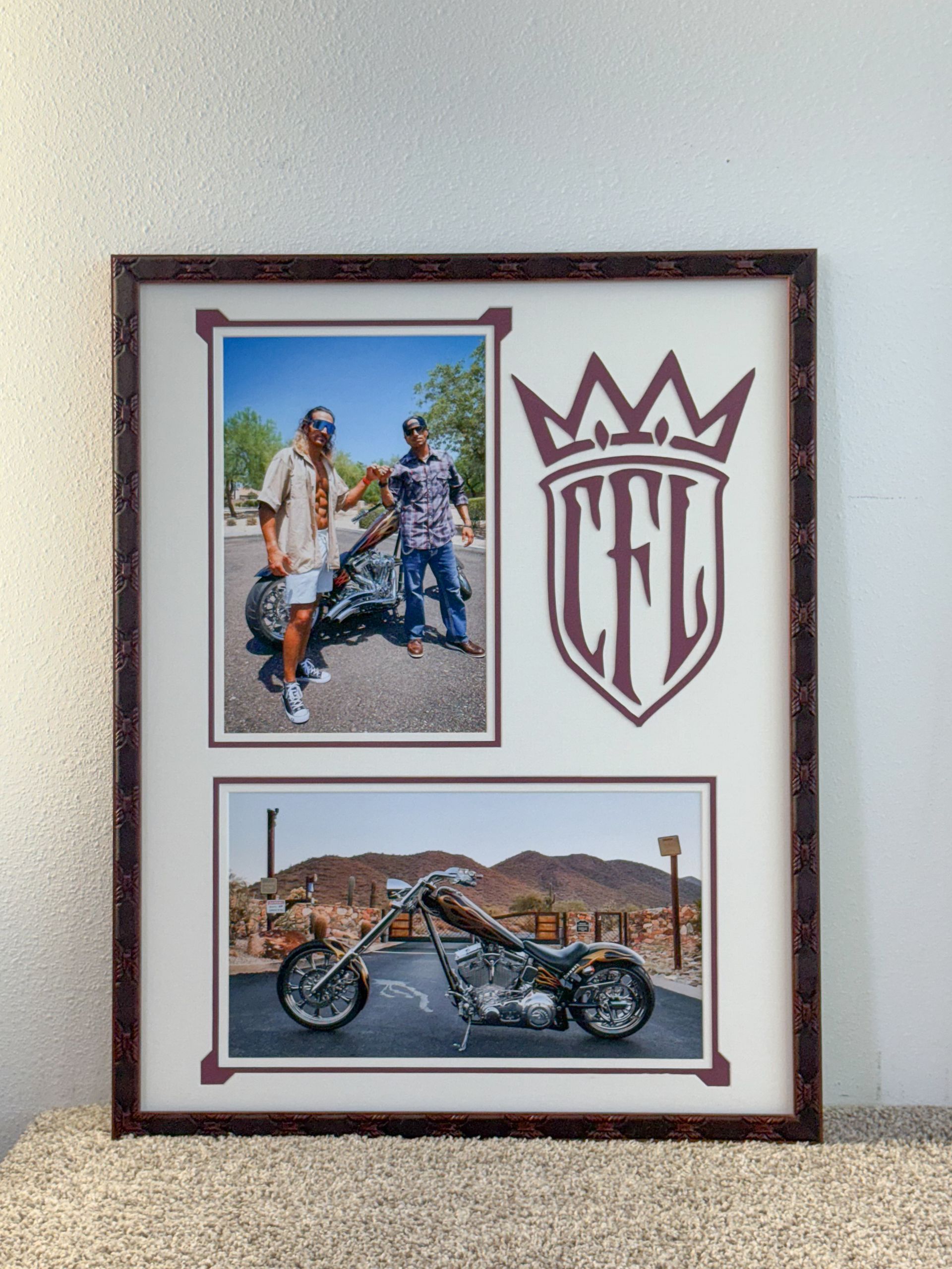 Framed collage of a motorcycle, riders, and a crown-style logo on a white wall