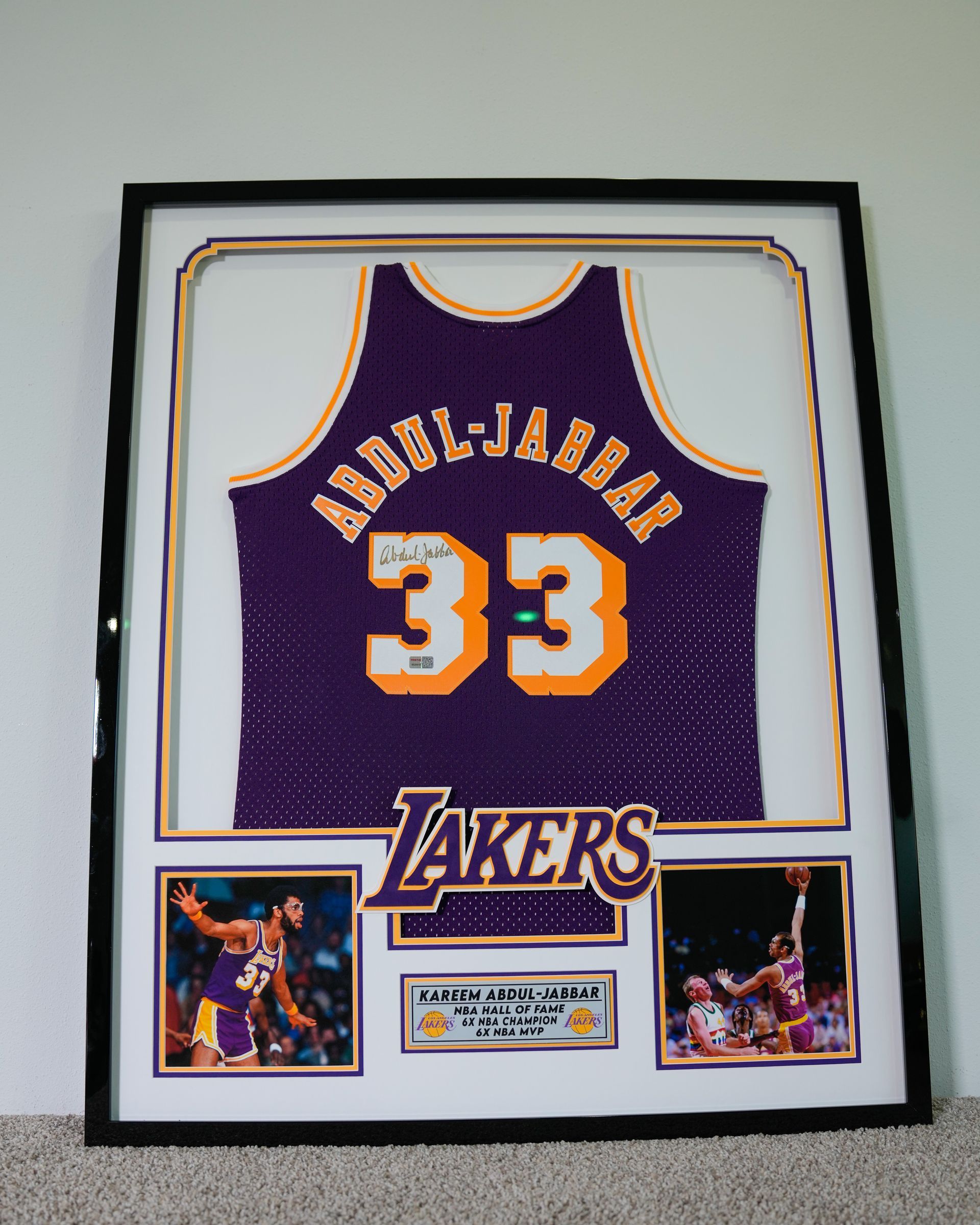 Framed purple and gold Lakers jersey with number 33 and photos displayed below