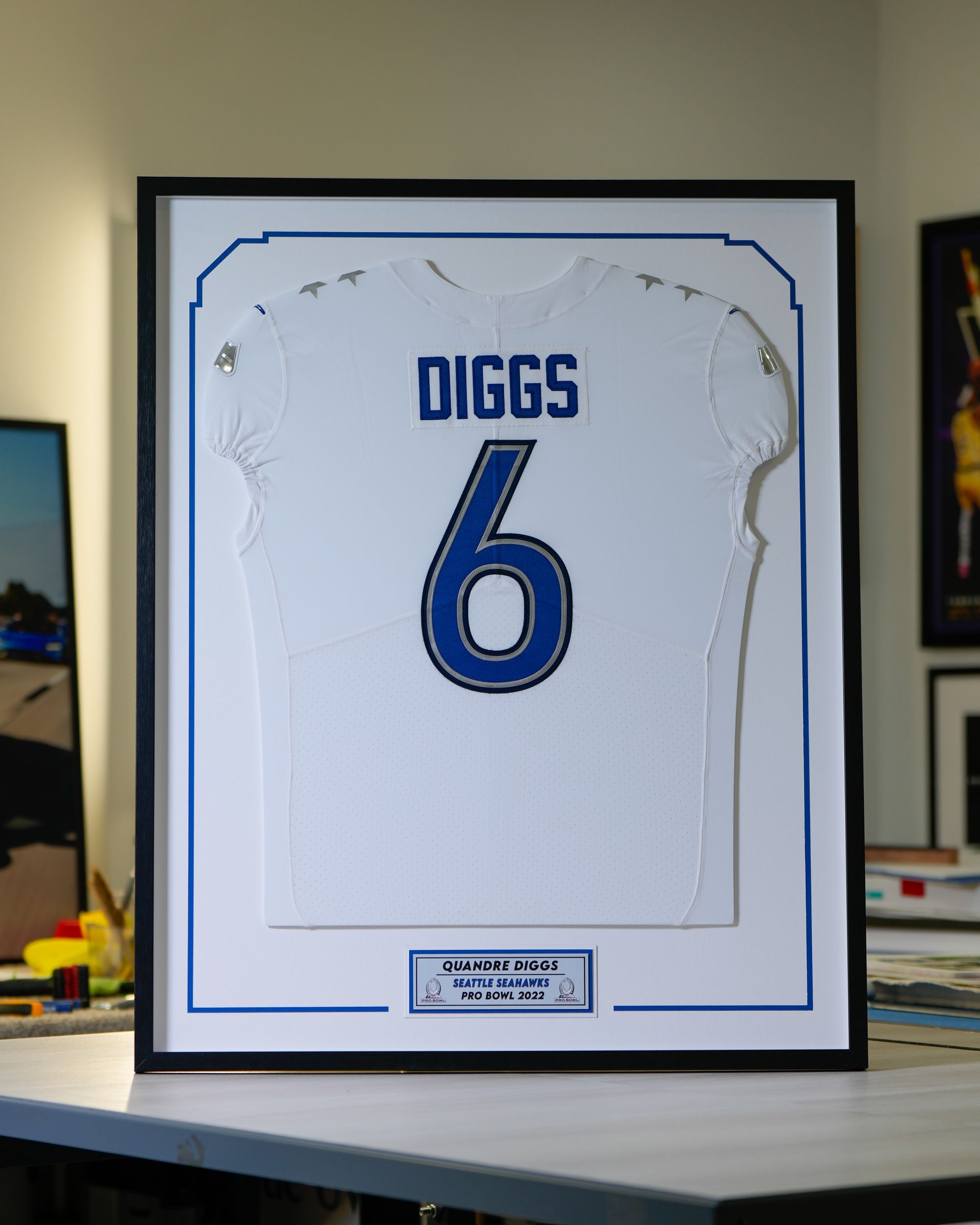 Framed white jersey with blue name DIGGS and number 6 displayed on a table.