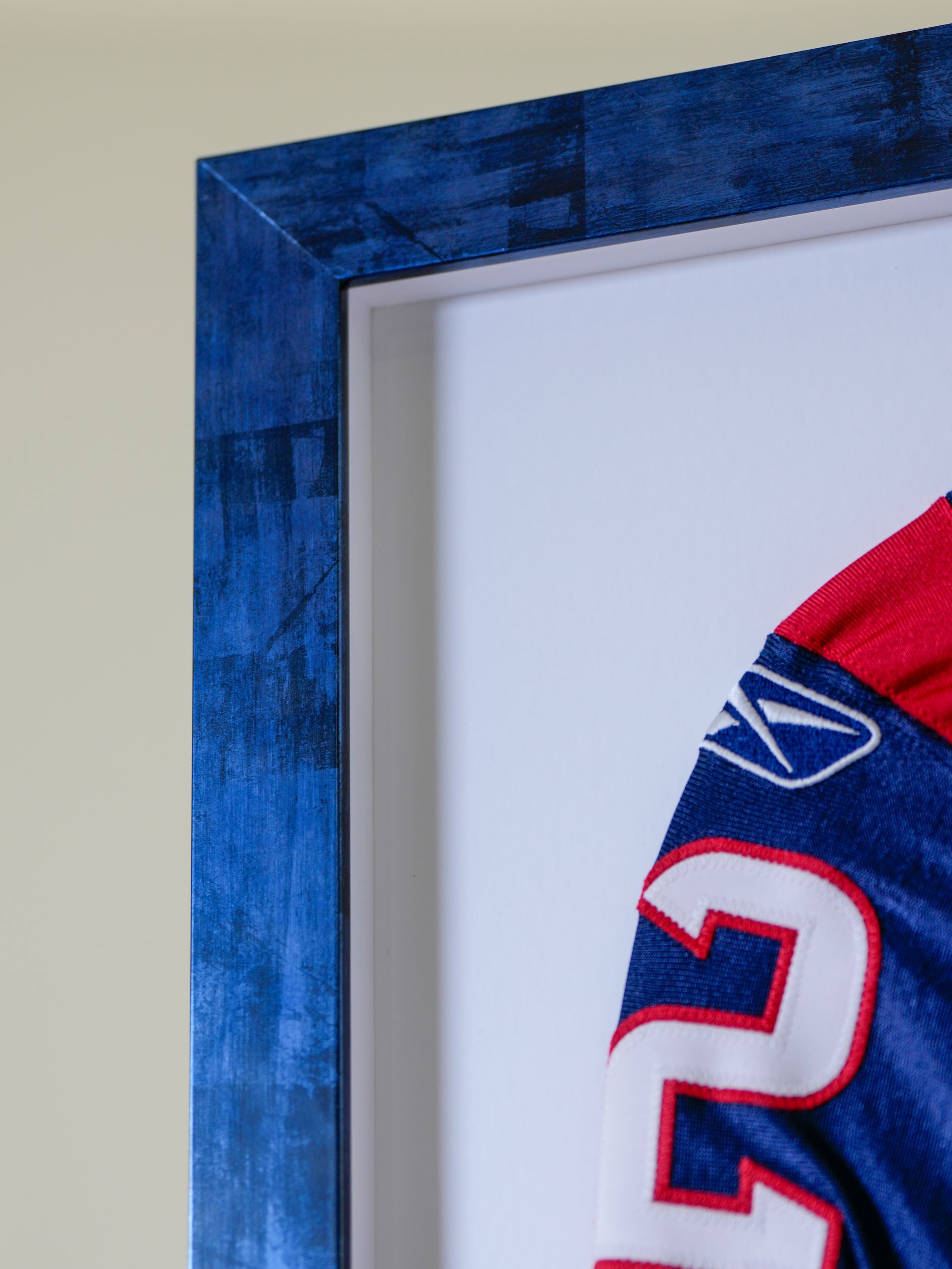 Framed sports jersey in blue-and-red frame, showing the number 2 on white fabric