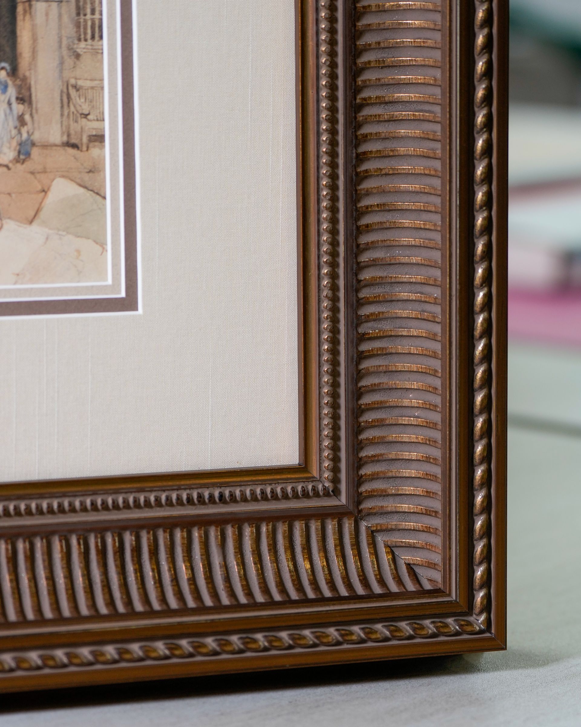 Close-up of a brown, ornate picture frame with a beige mat