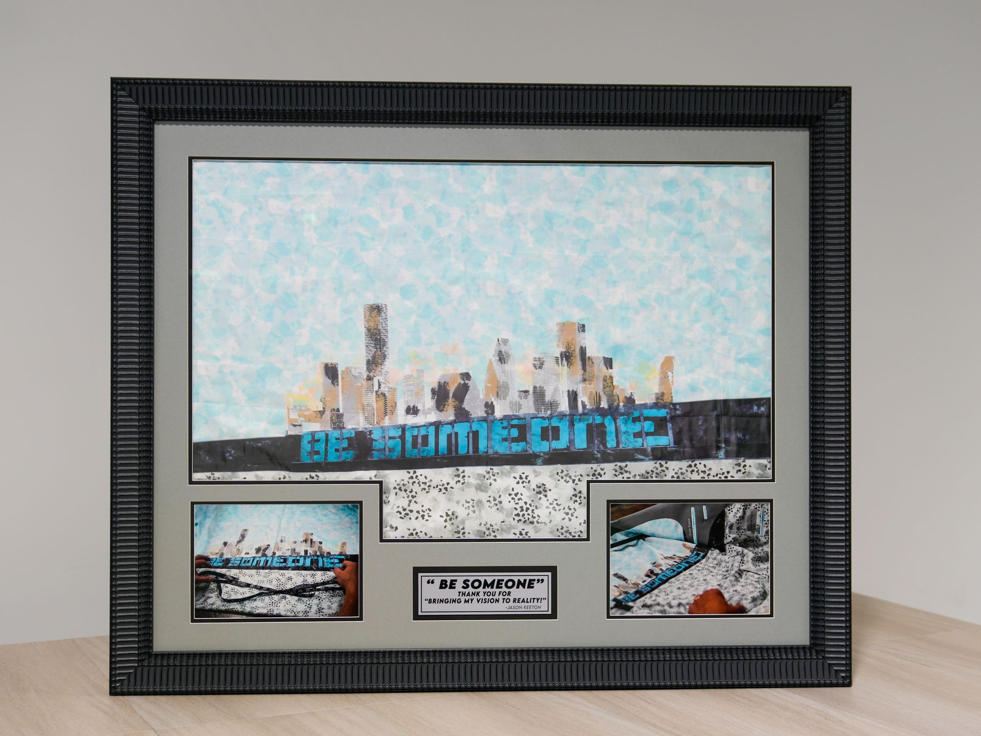 Framed collage with a blue cityscape and several small photos on a light wall