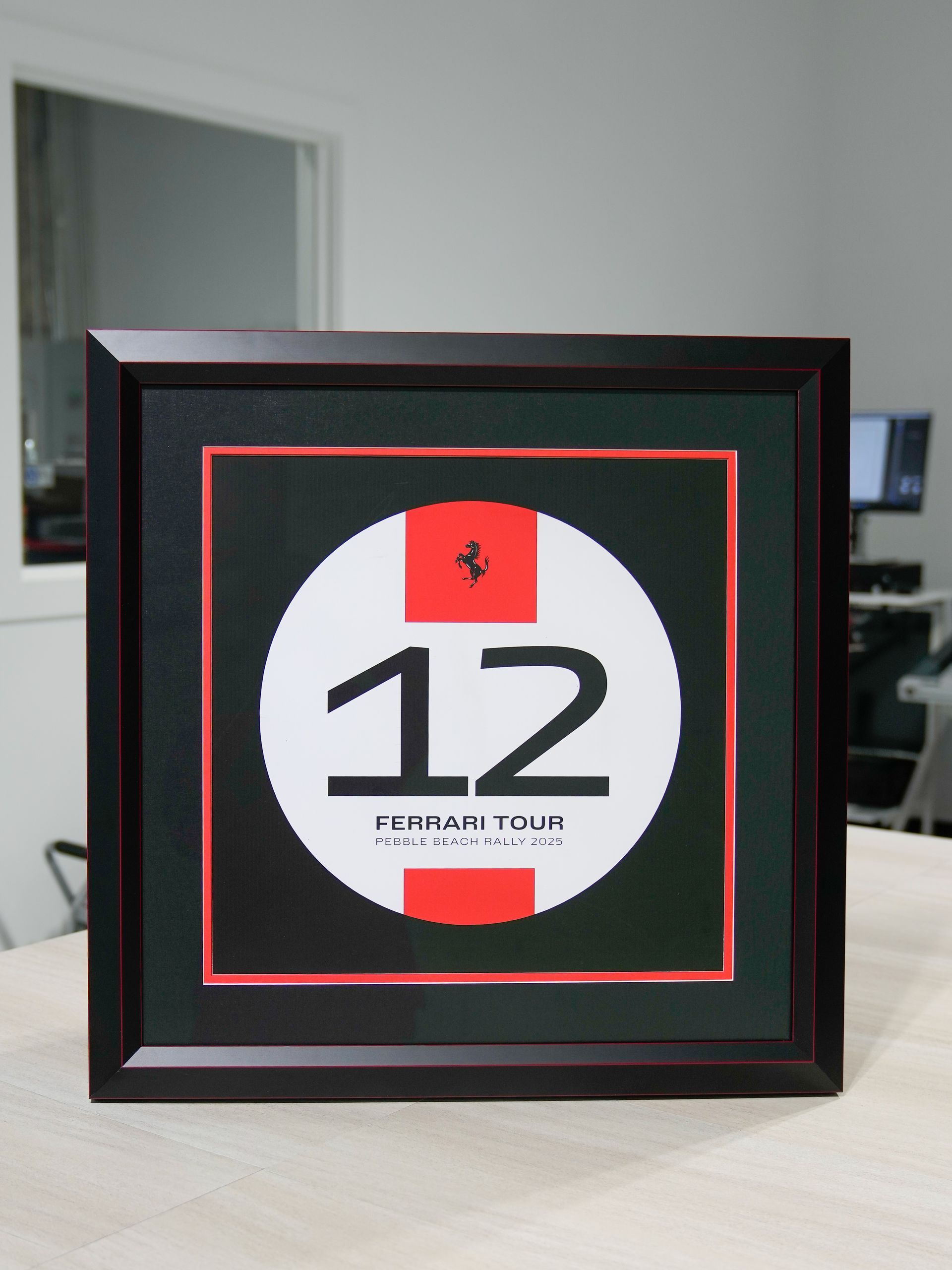 Framed sign with a large “12” in black and red on a white circle, displayed indoors.