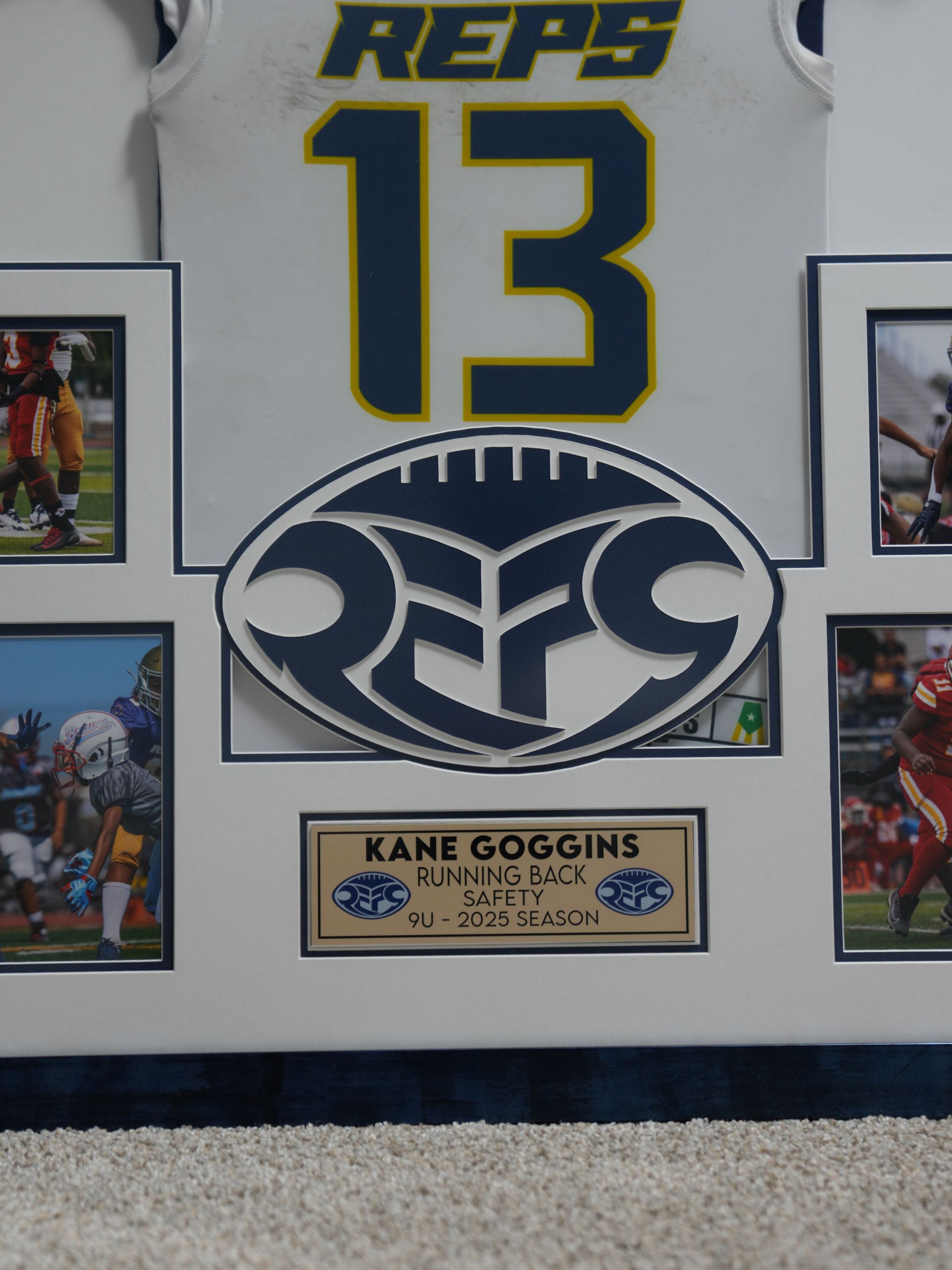 Framed sports jersey display with number 13 and Kane Soggins nameplate, centered on a large logo