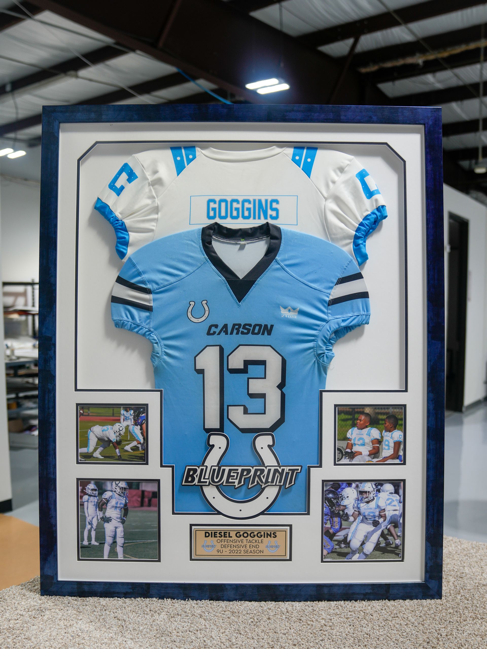 Framed light blue football jersey display with name Goggins and number 13, surrounded by small game photos.