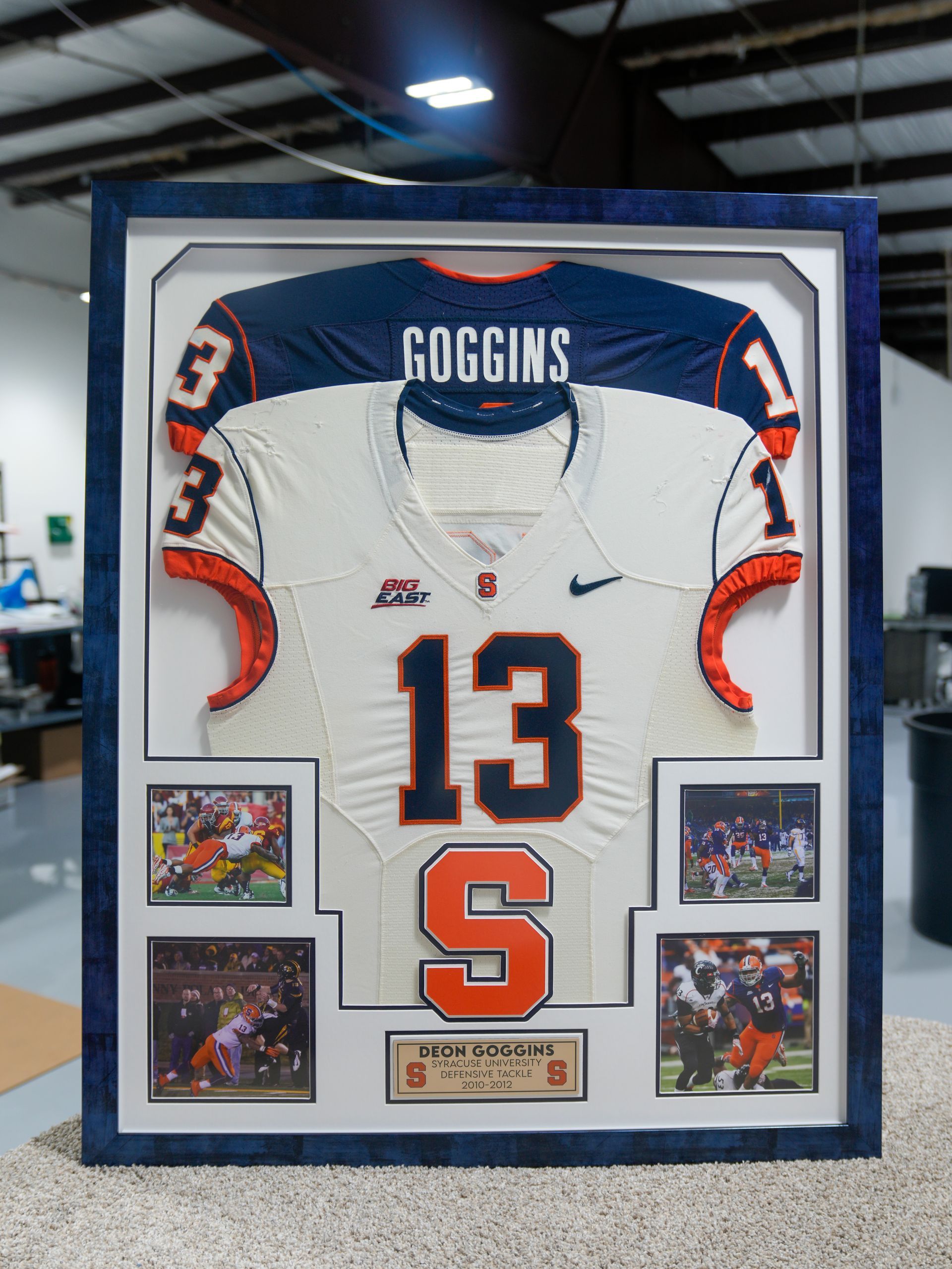 Framed football jersey display, white jersey with orange and navy trim, number 13 and “ROGGINS” on top.