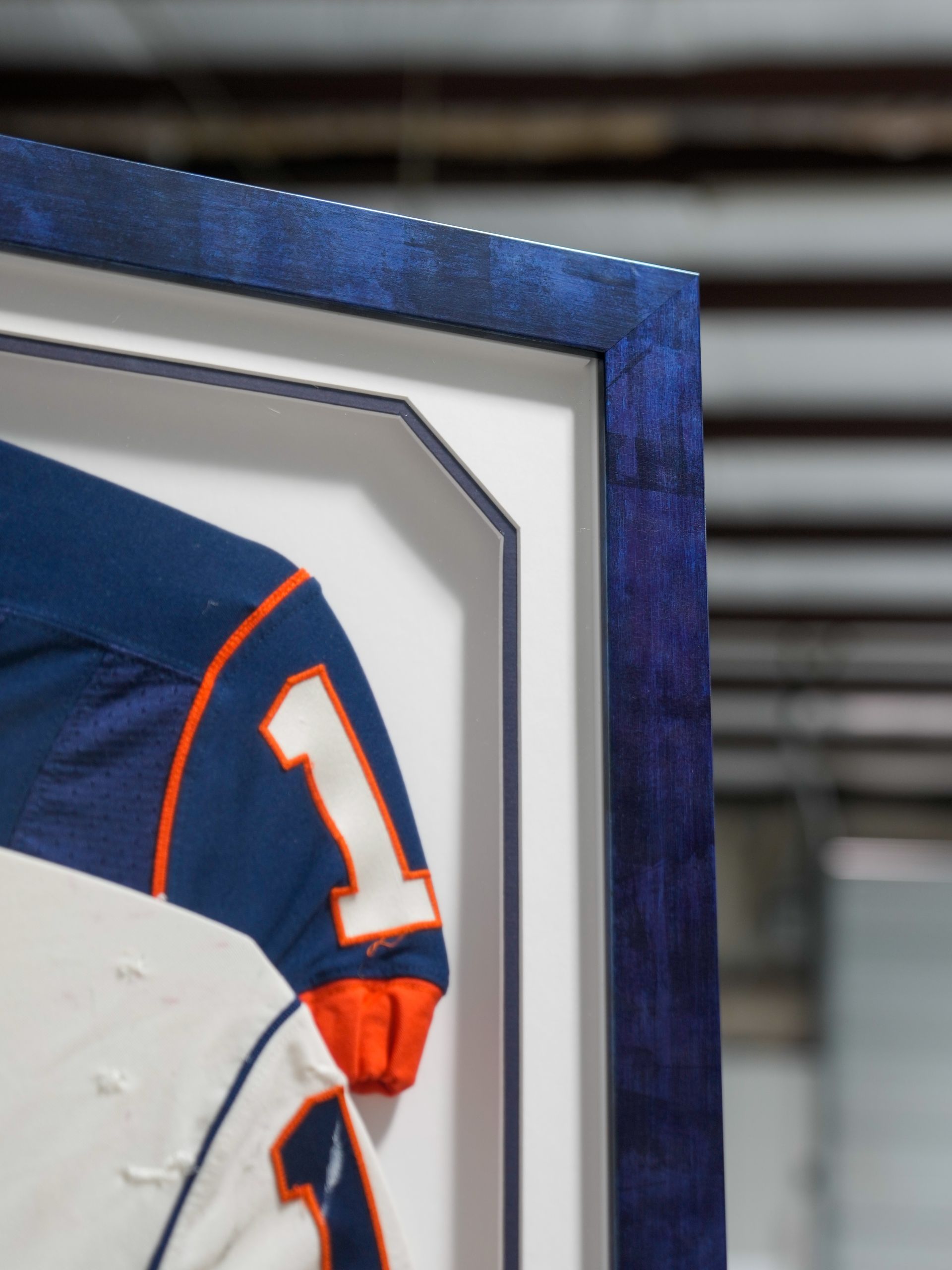 Framed blue and orange football jersey with number 1 on display