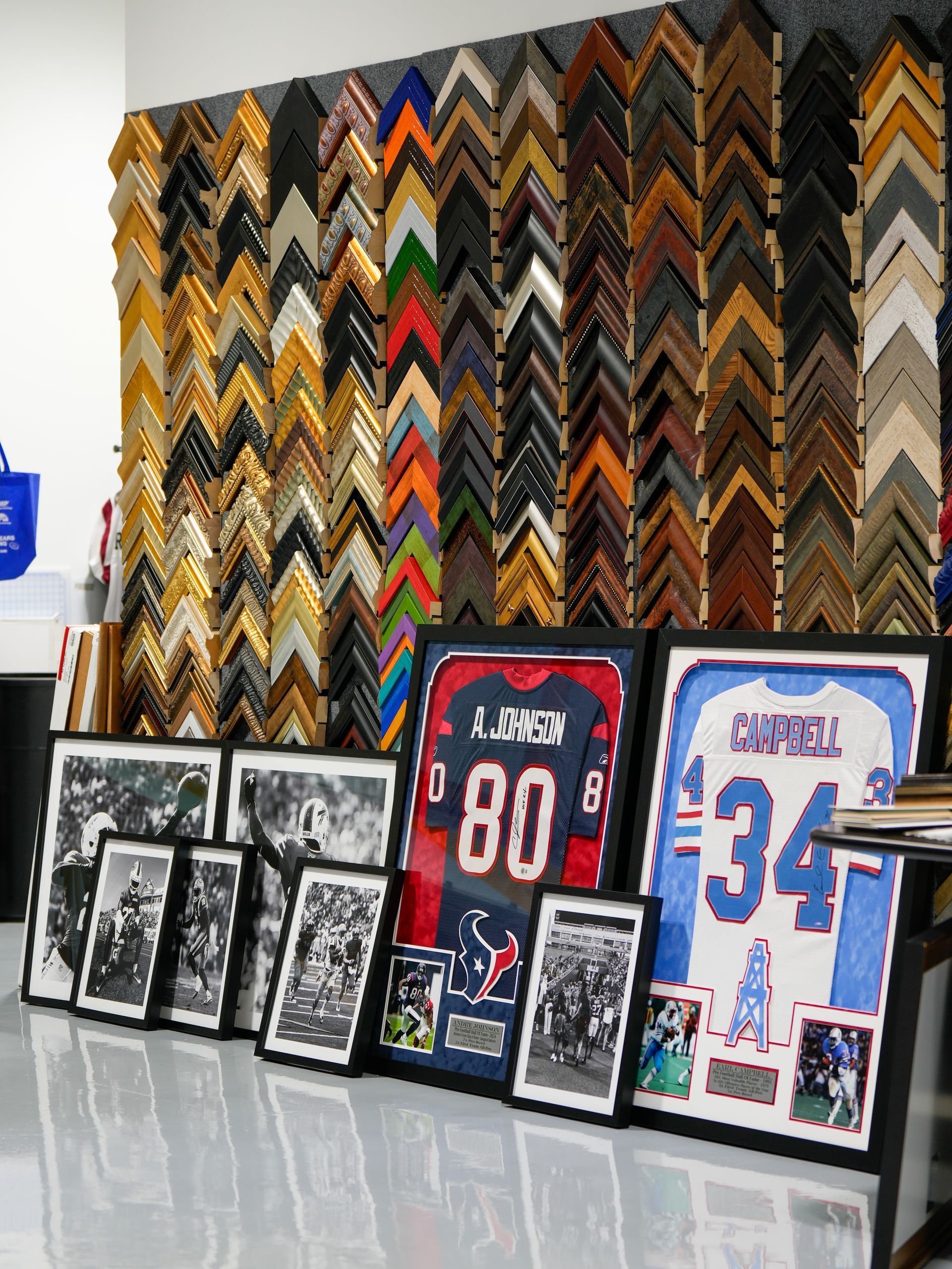 Wall of colorful picture frames and framed sports jerseys displayed on a shiny floor indoors