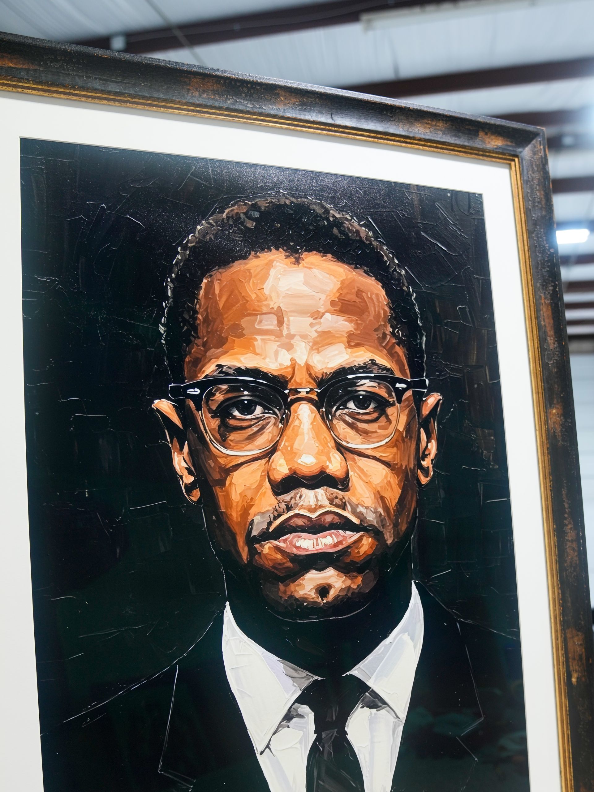 Framed portrait of a man in a dark suit, white shirt, tie, and glasses on a black background