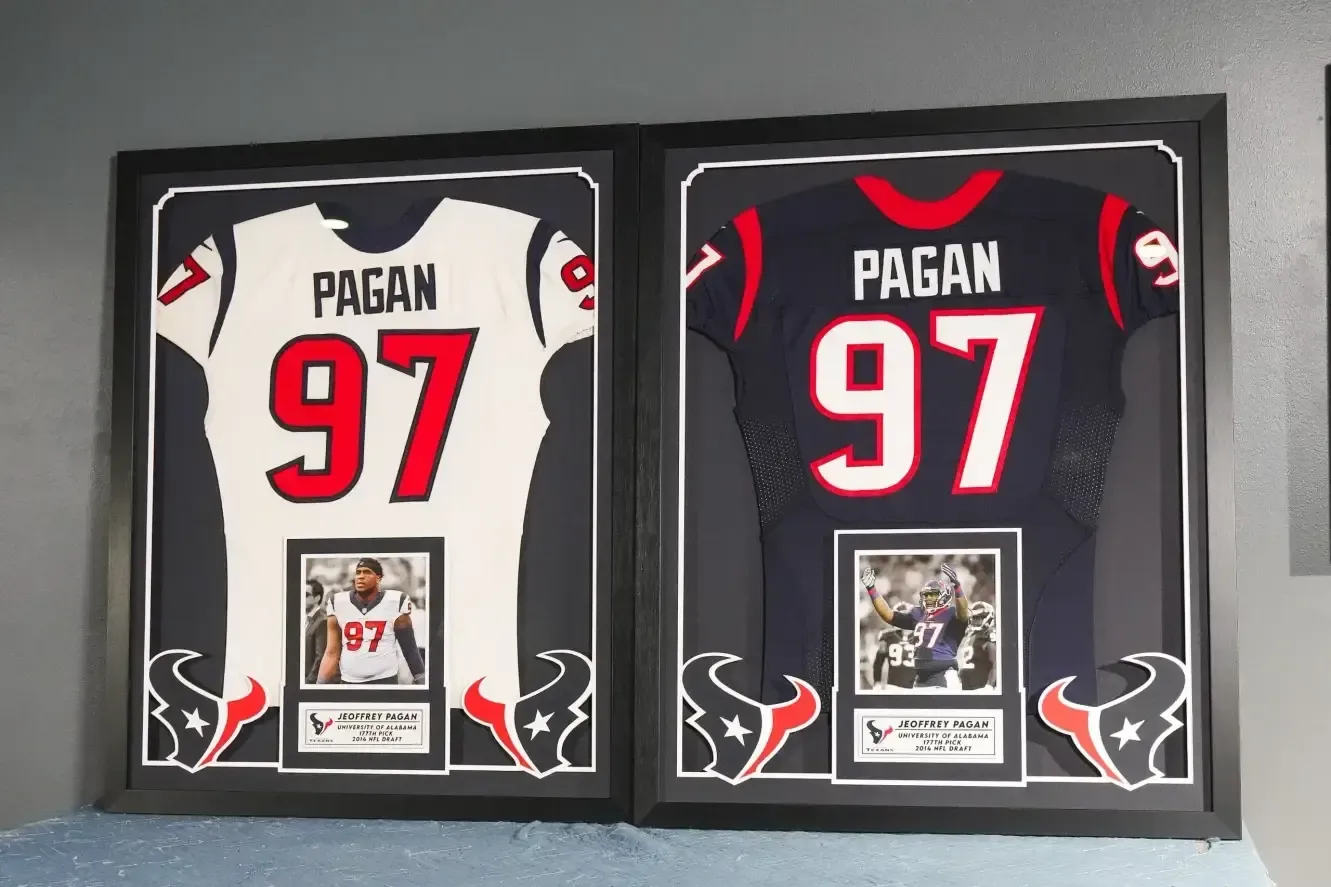 Two framed football jerseys, white and black, both labeled PAGAN 97, displayed side by side.