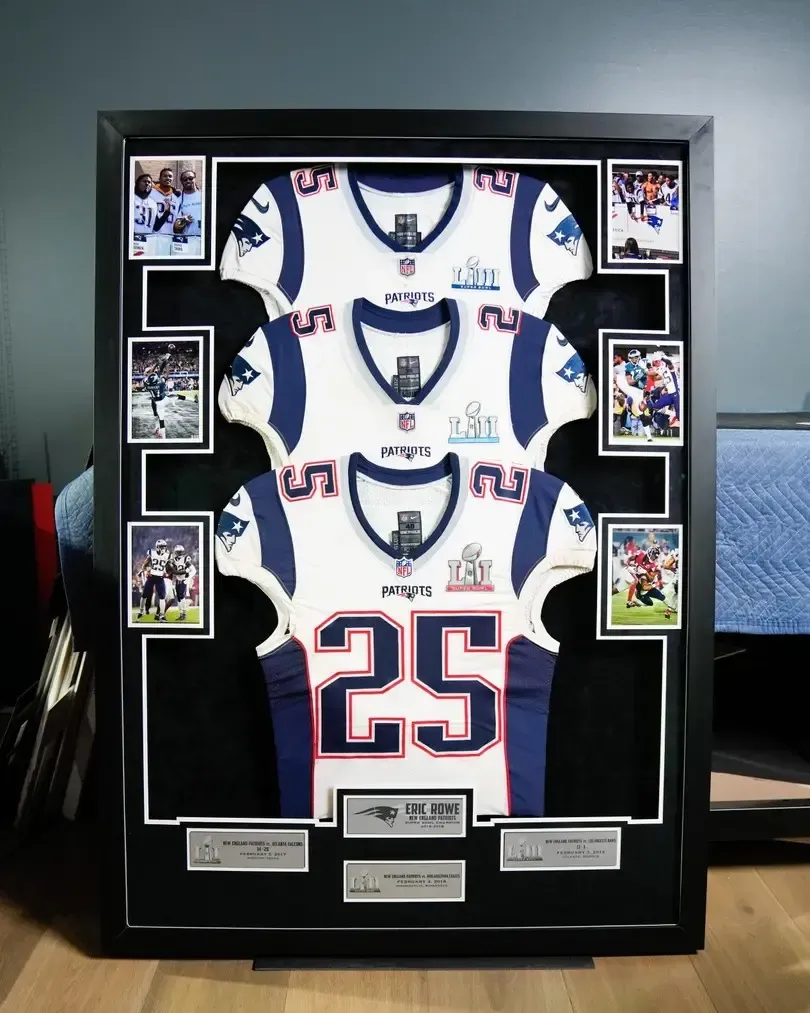 Framed display of three New York Giants jerseys with photos and plaques on a desk
