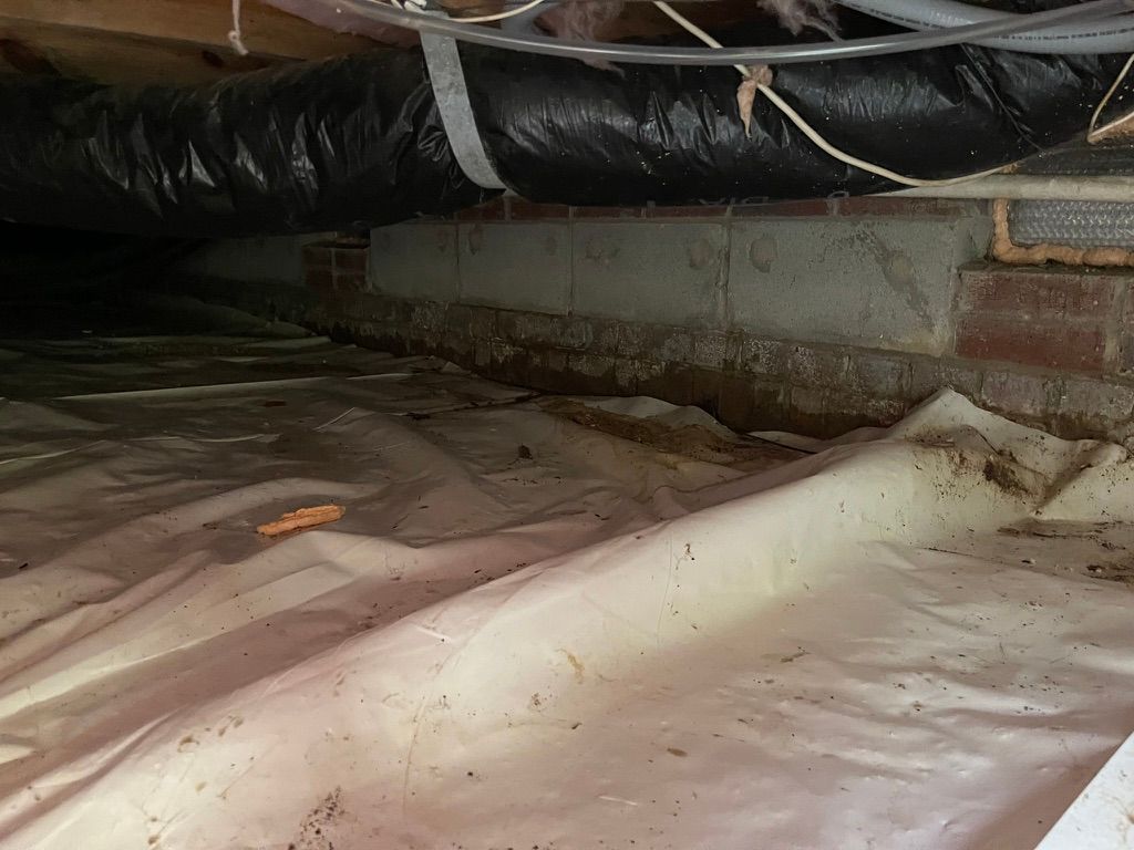 A crawl space filled with plastic and a pipe.