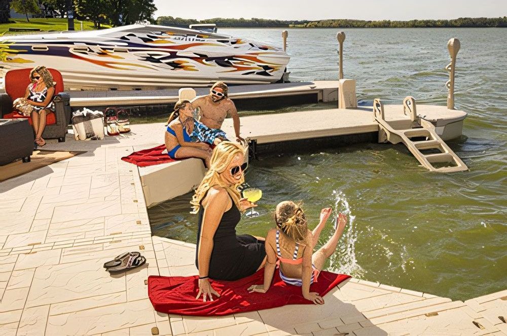 A family sits on a dock with a boat in the background