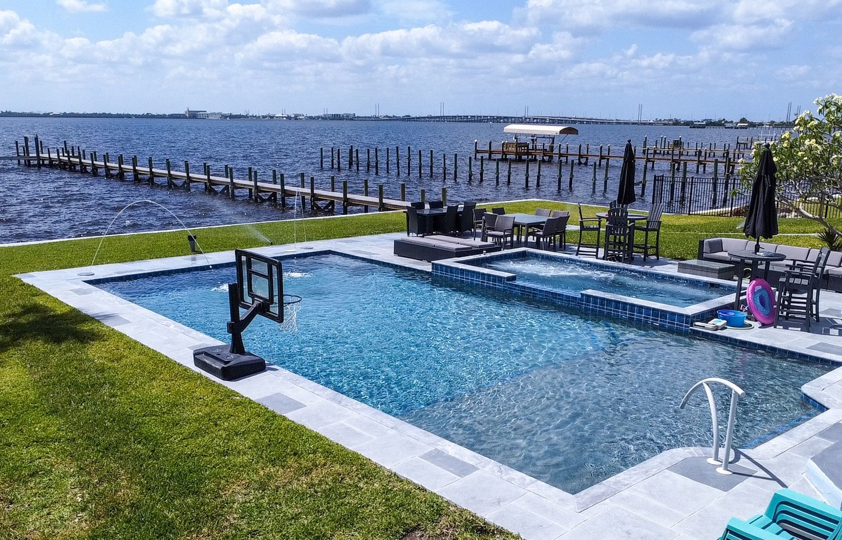 A large swimming pool with a view of the water and a basketball hoop.