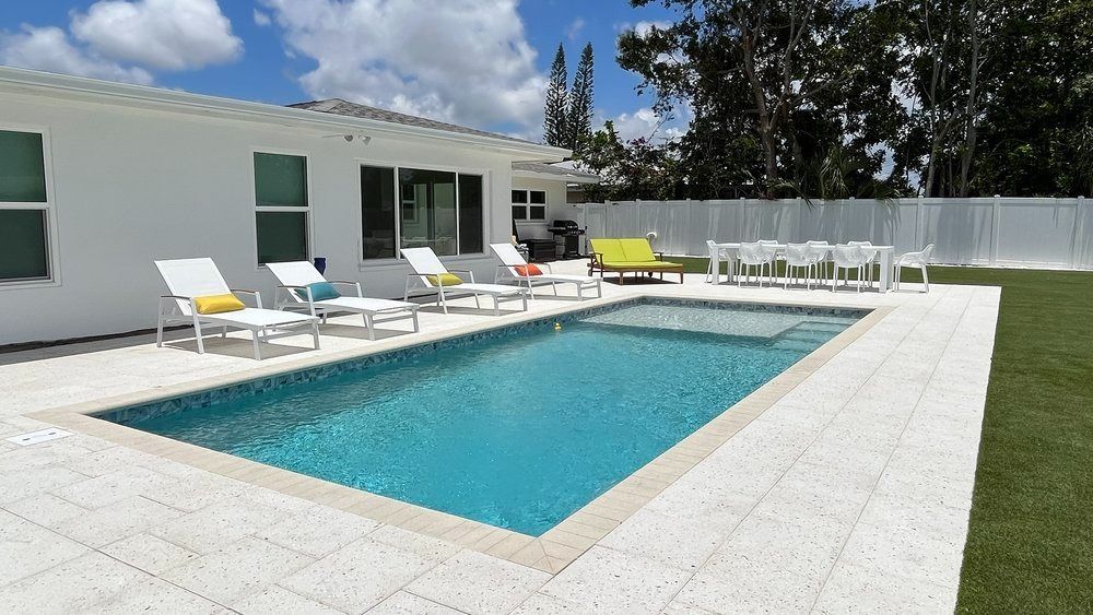 A large swimming pool in front of a white house
