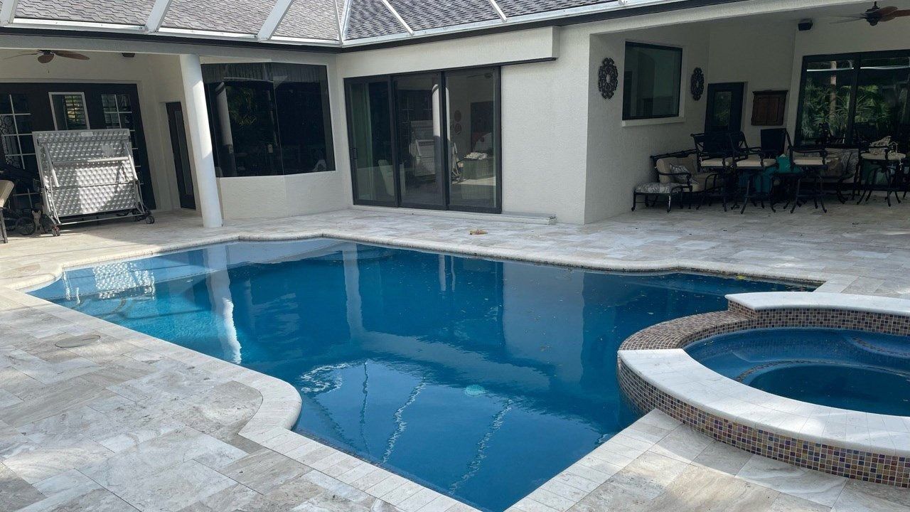 A large swimming pool with a hot tub in the backyard of a house.