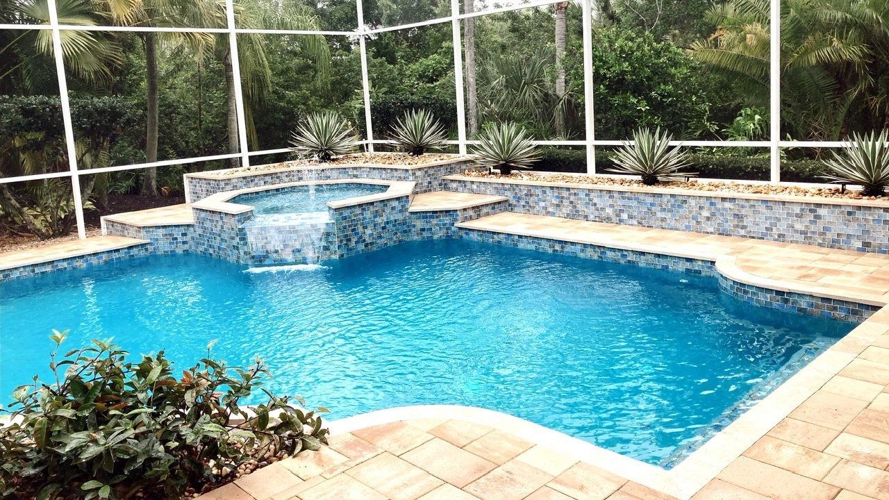 A large swimming pool is surrounded by a screened in area.