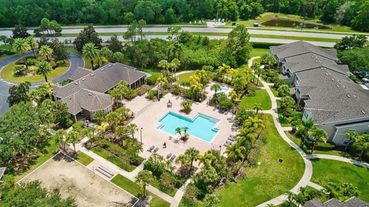 An aerial view of a swimming pool surrounded by buildings and trees.
