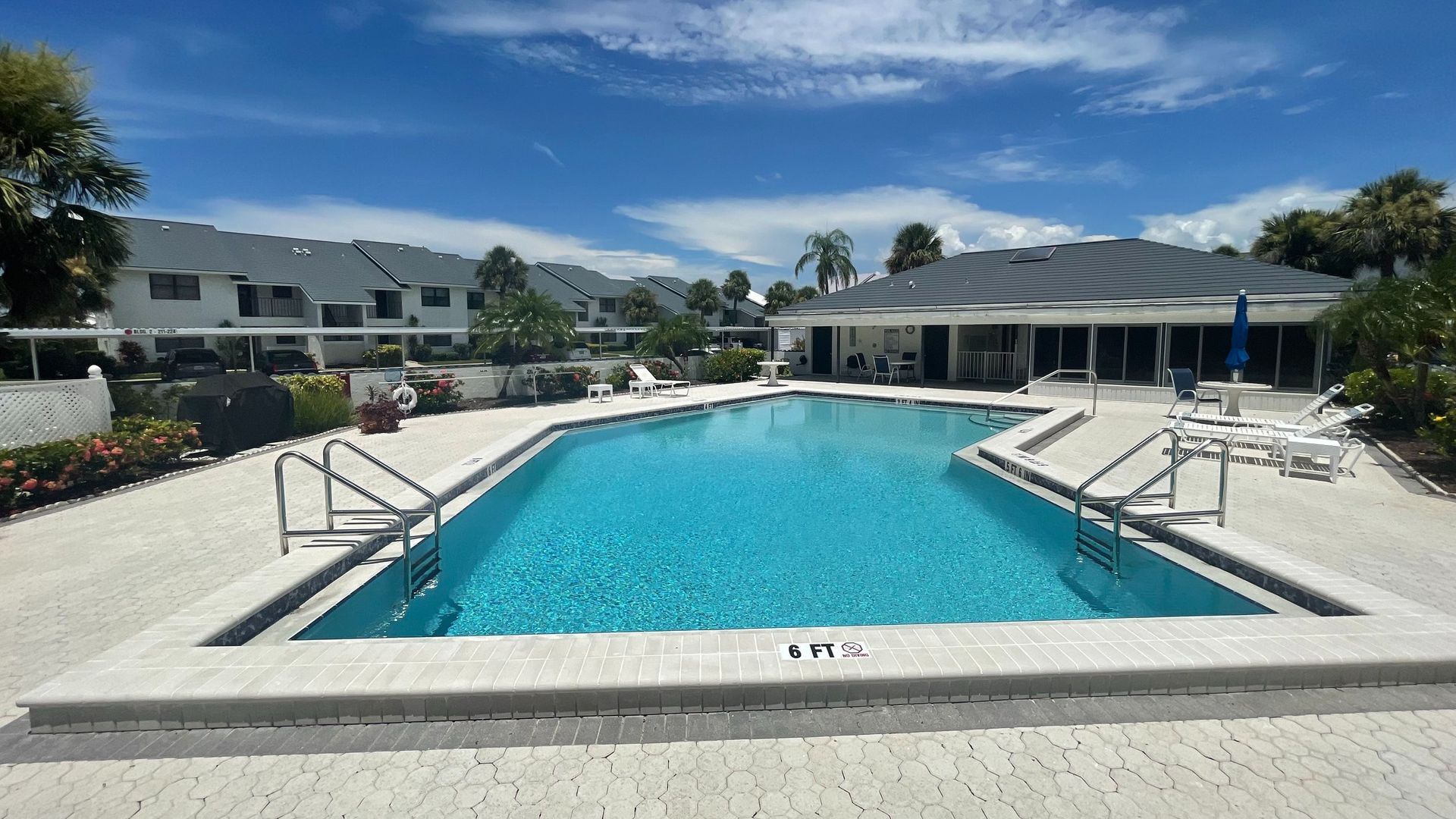 A large swimming pool in a residential area with a clubhouse in the background