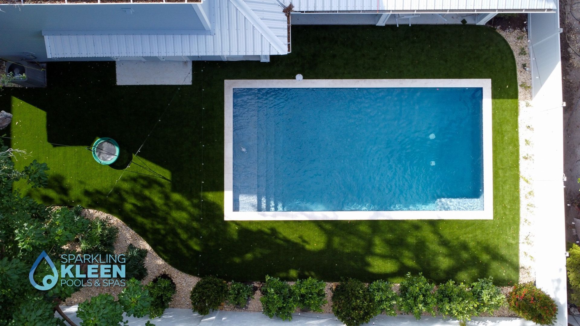 An aerial view of a large swimming pool in the backyard of a house.