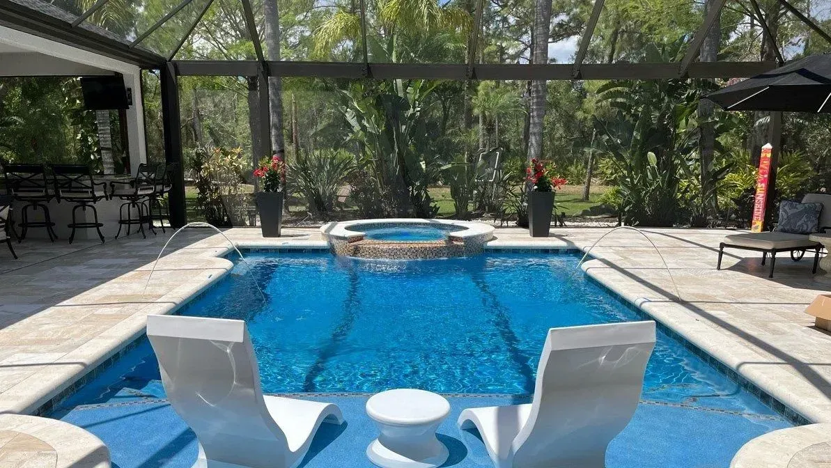 Swimming pool with blue water and white lounge chairs; spa in background.