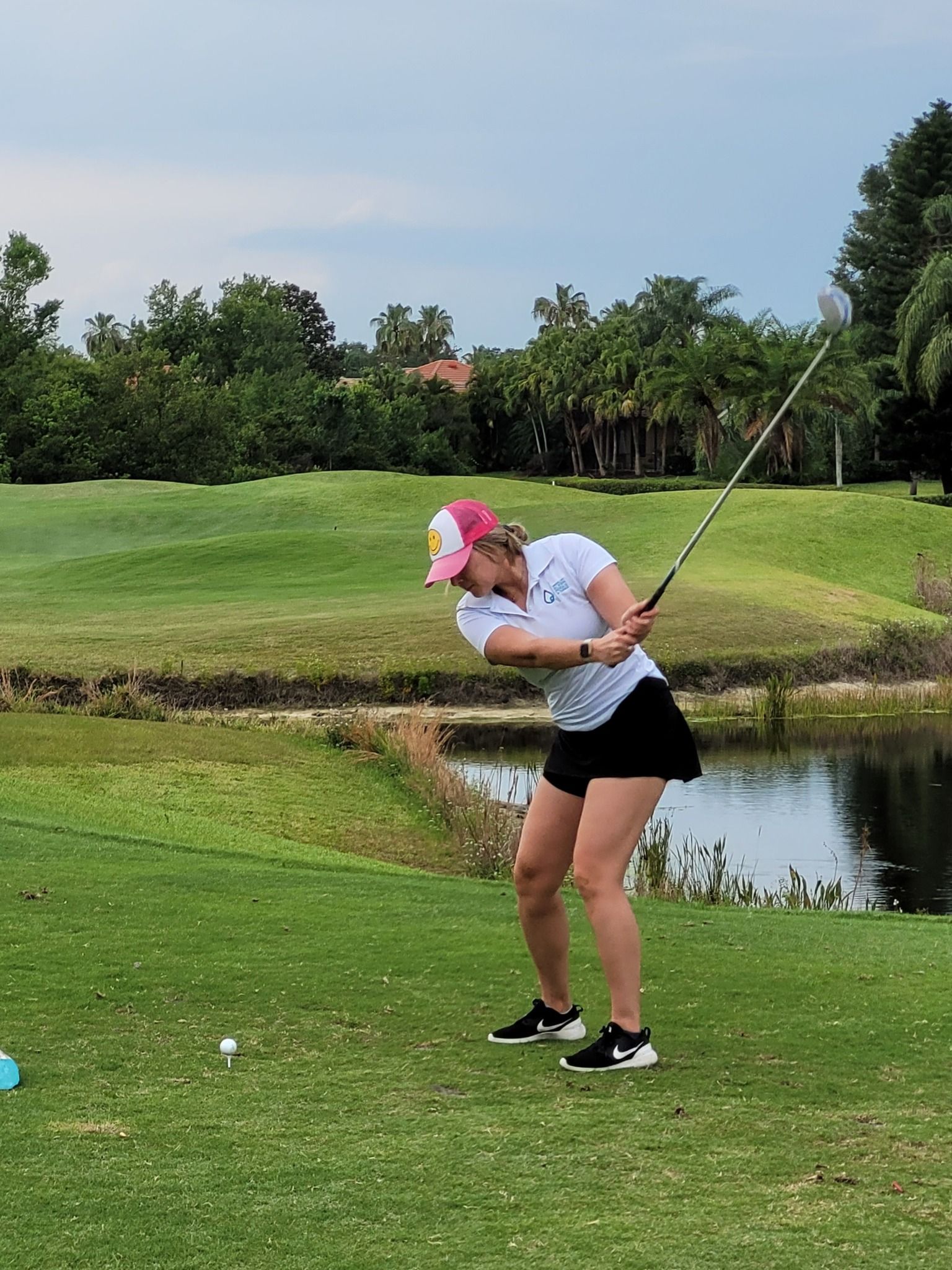 A woman is swinging a golf club on a golf course.