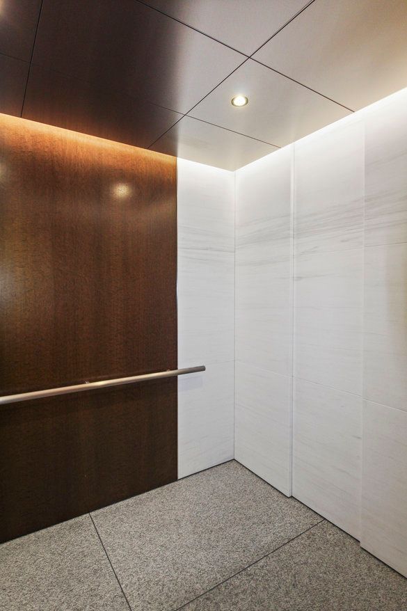 An elevator with a wooden wall and a white wall.