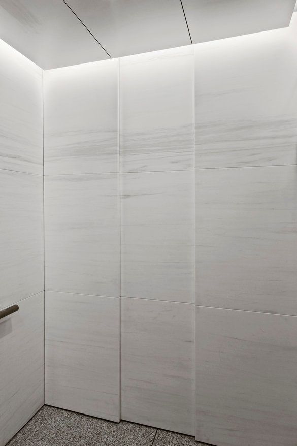 A bathroom with white tiles and a marble floor.