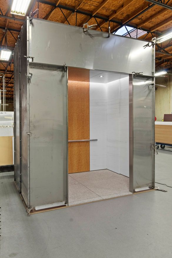 A stainless steel elevator with a wooden door in a building.