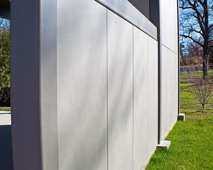 A large concrete wall is surrounded by grass and trees.
