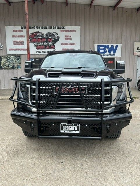 Black lifted pickup truck with heavy-duty front grille guard parked outside a shop.