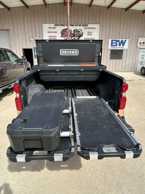 Pickup truck bed with two slide-out cargo drawers and a large black storage case in a garage setting