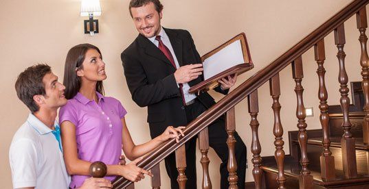 Estate agent with young couple on ladder
