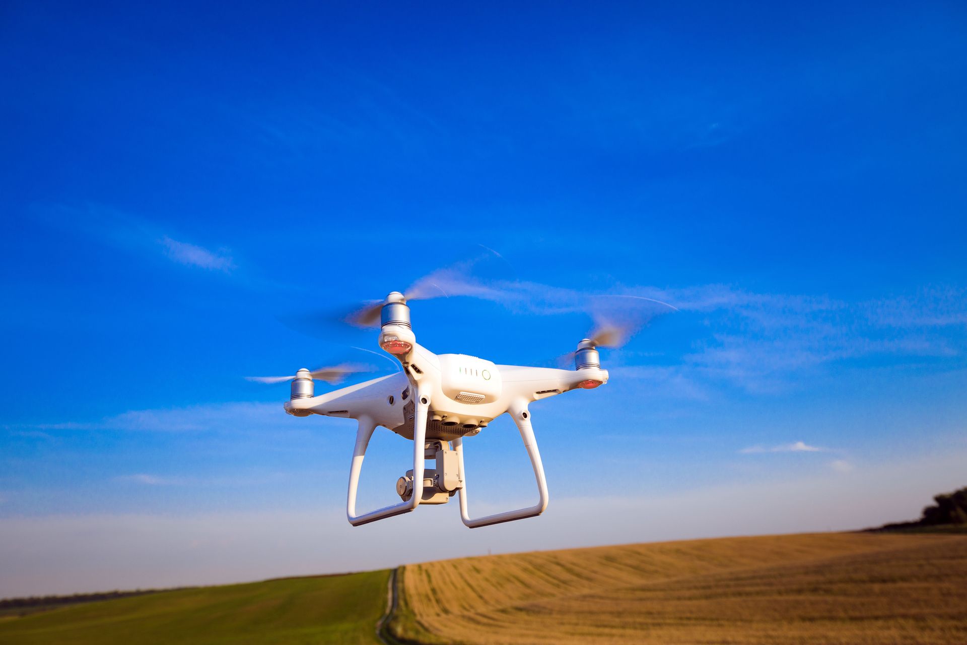 A drone is flying over a field in the sky.