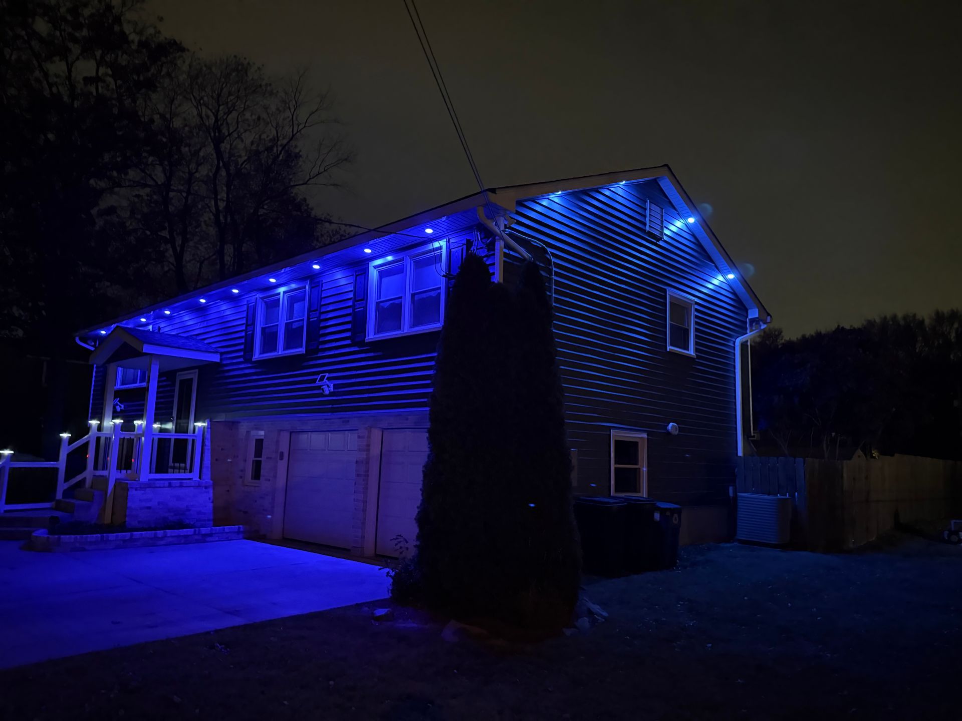 A house at night illuminated by bright blue decorative lights along the roofline and porch.