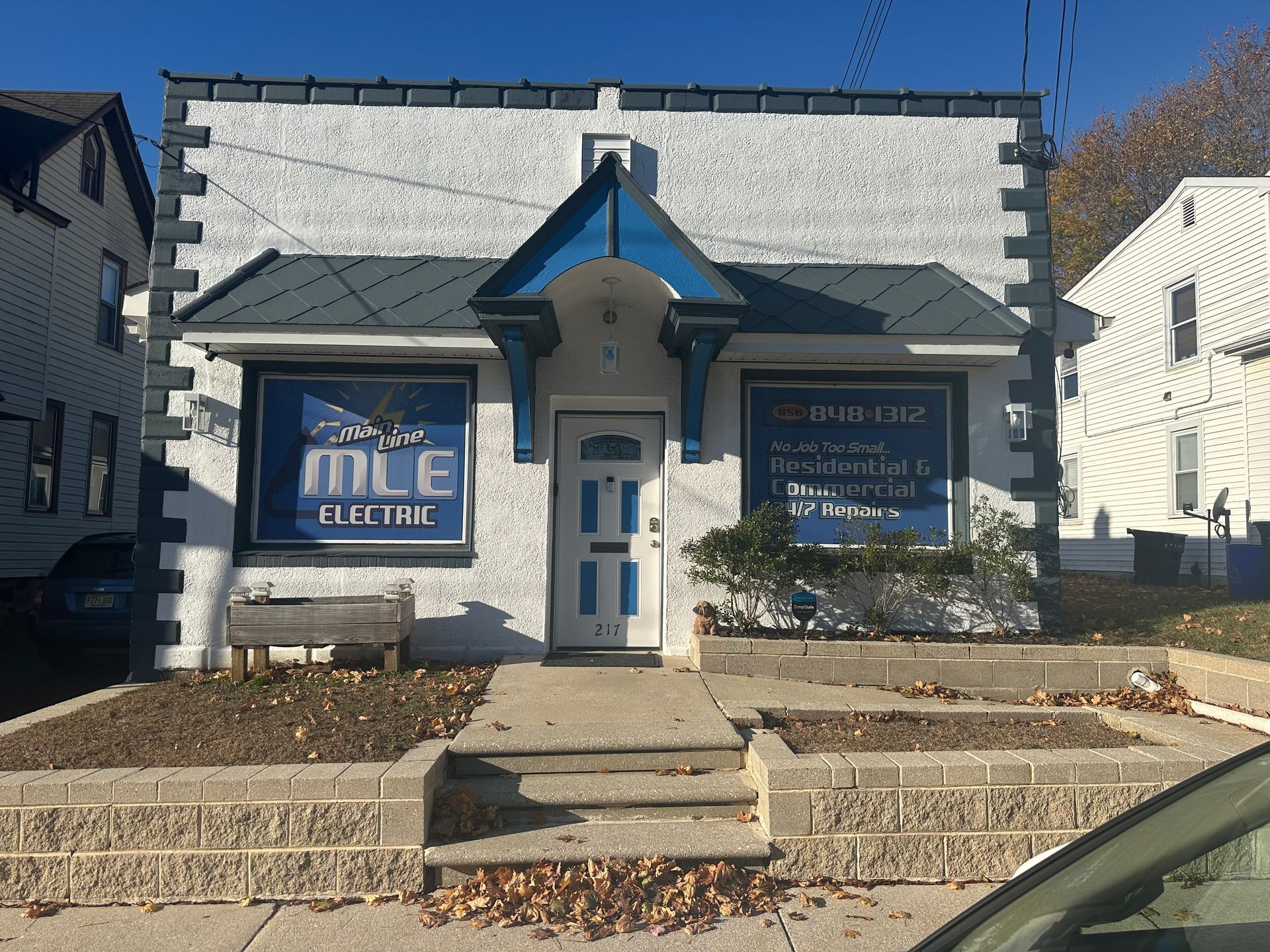 A white, single-story commercial building with a blue entrance awning and blue signage for 