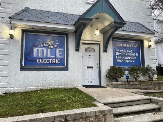 Main Line Electric office building featuring blue and white signage with business name, address 217, and stone steps.