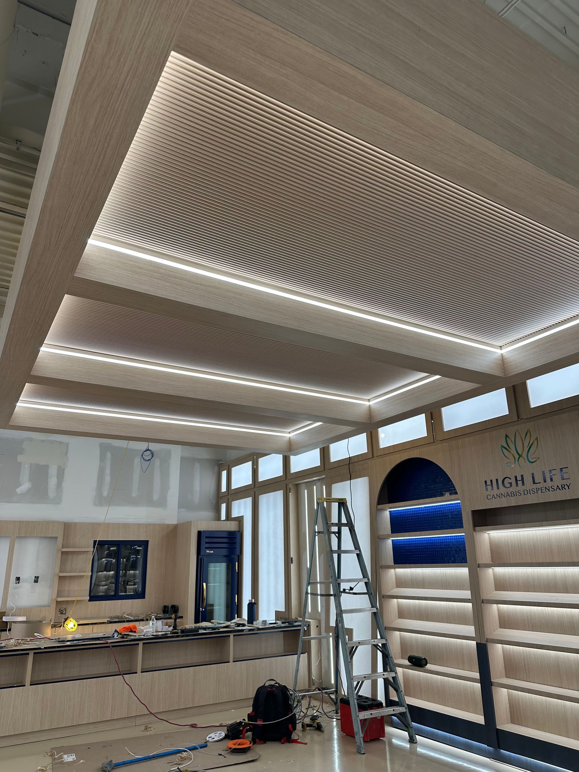 Construction in a retail store interior featuring a modern, undulating wooden wave ceiling with integrated lighting.