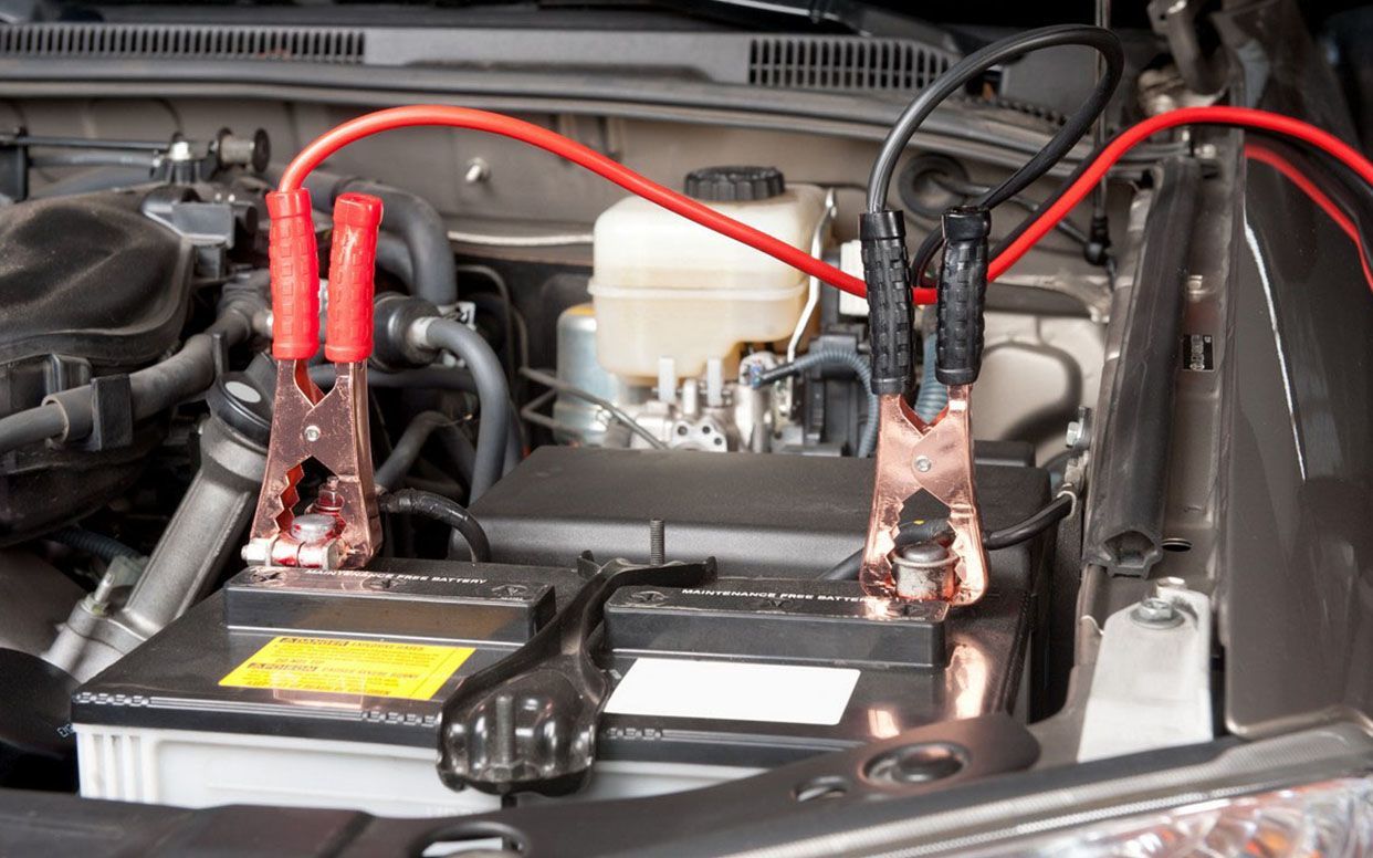 Learn More About Us Car battery with jumper cables connected, providing a jump start.